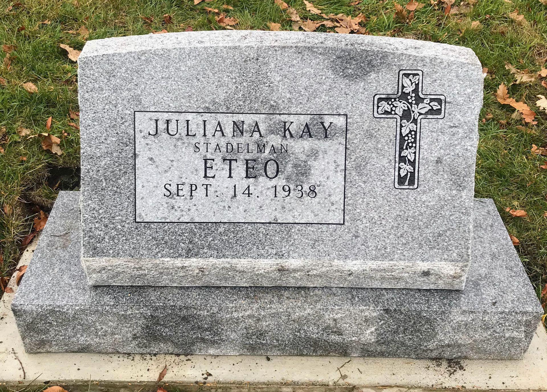A gravestone with a cross on it in a cemetery