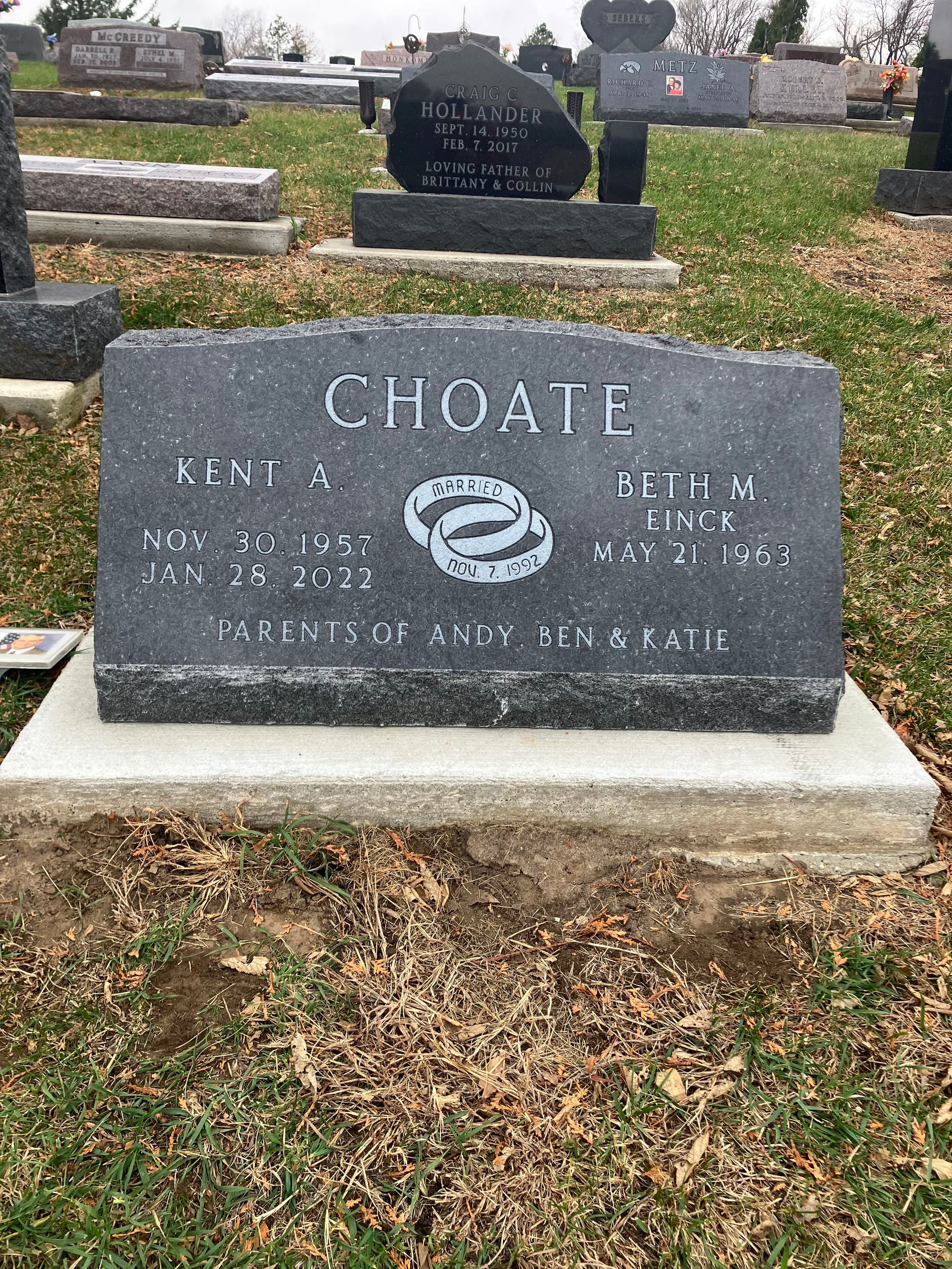 A gravestone in a cemetery with two wedding rings on it