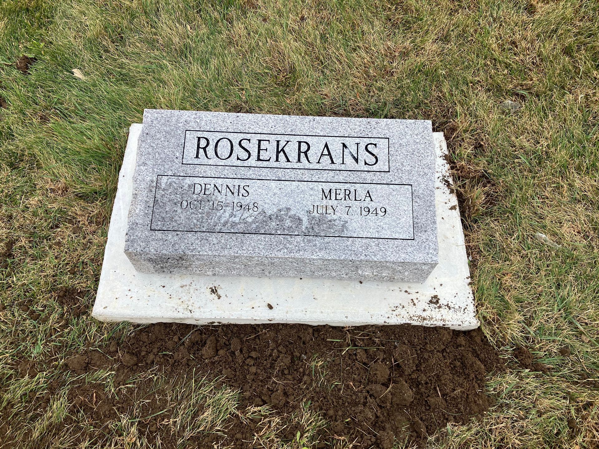 A gravestone is sitting on top of a lush green field