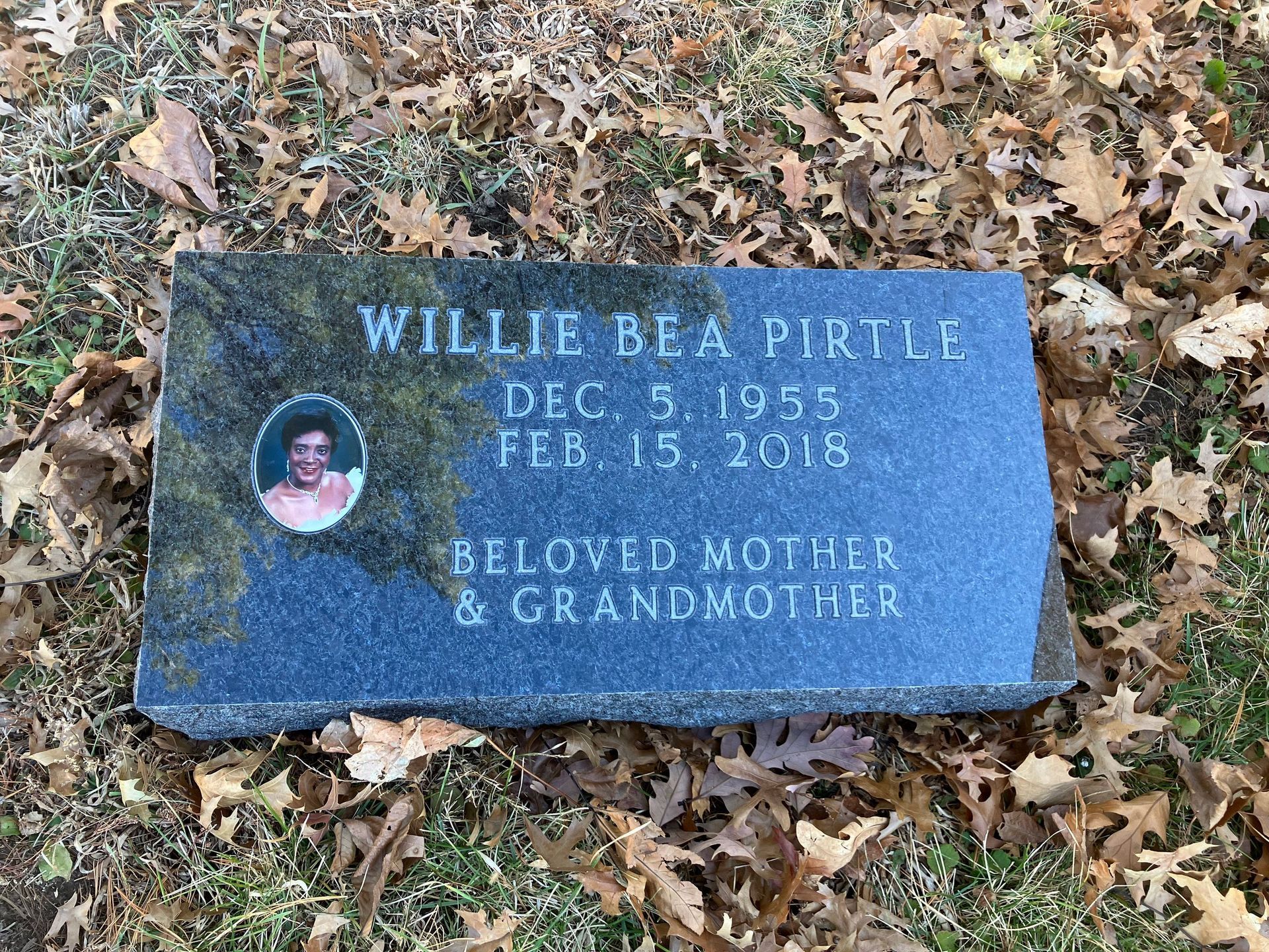 A gravestone in a cemetery with a picture of a man on it