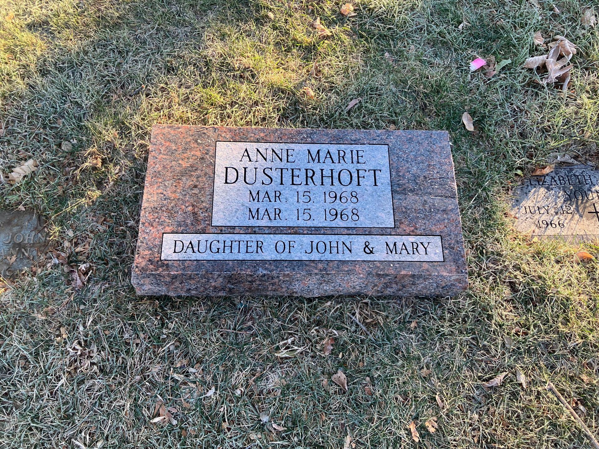A grave in a cemetery with two grave stones in the grass