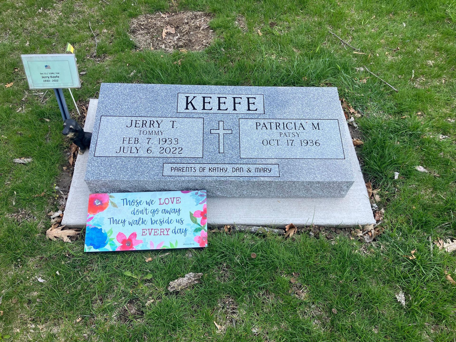 A gravestone with a sign on it in a cemetery