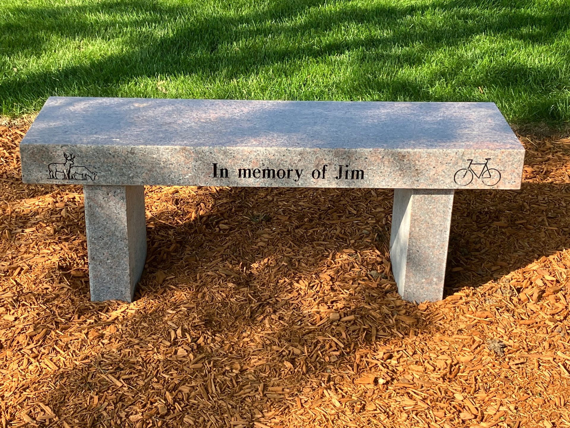 A stone bench is sitting on top of a pile of mulch in a park