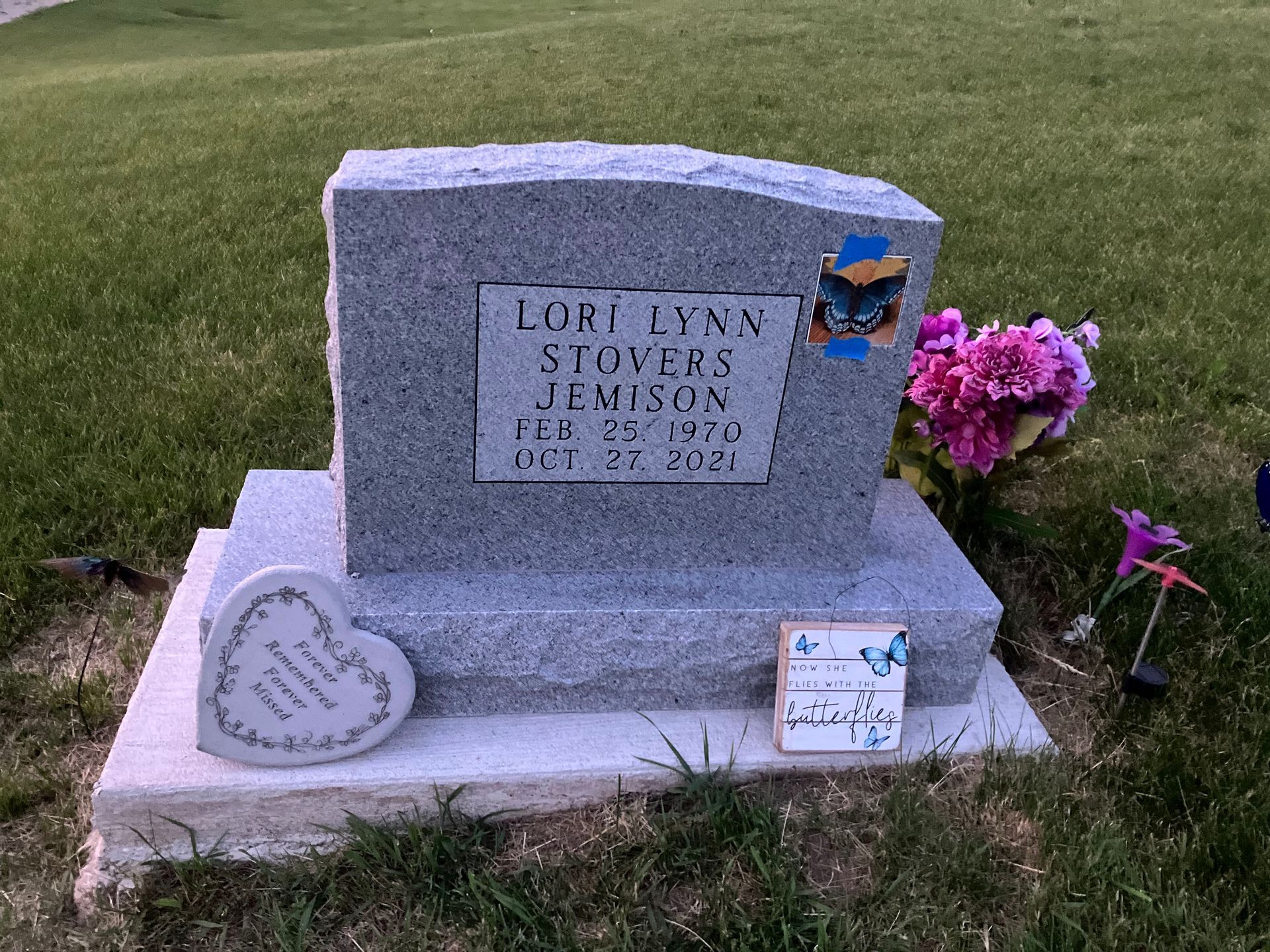 A gravestone in a cemetery with flowers and a heart on it