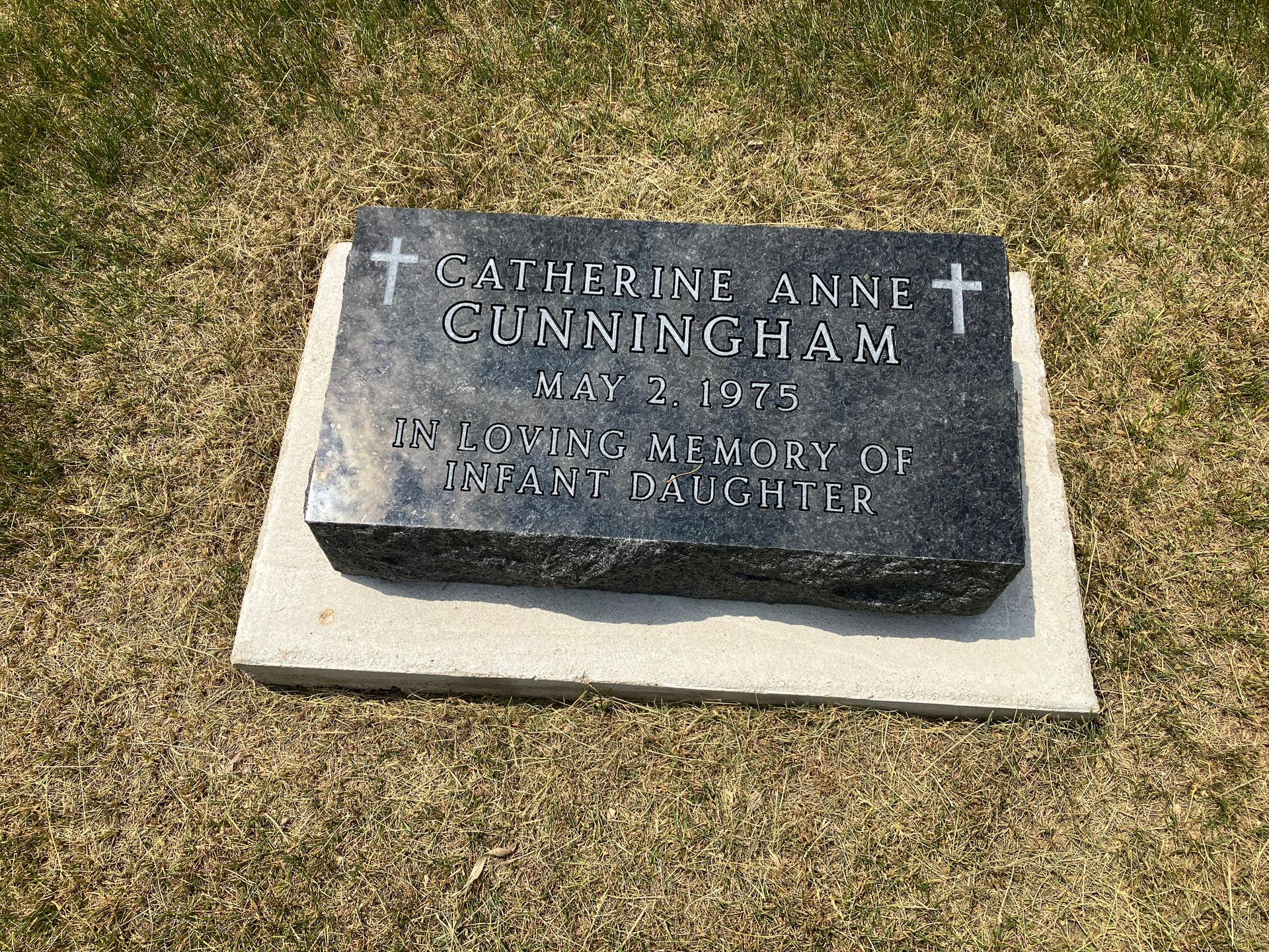 A gravestone for Cunningham is sitting on the grass