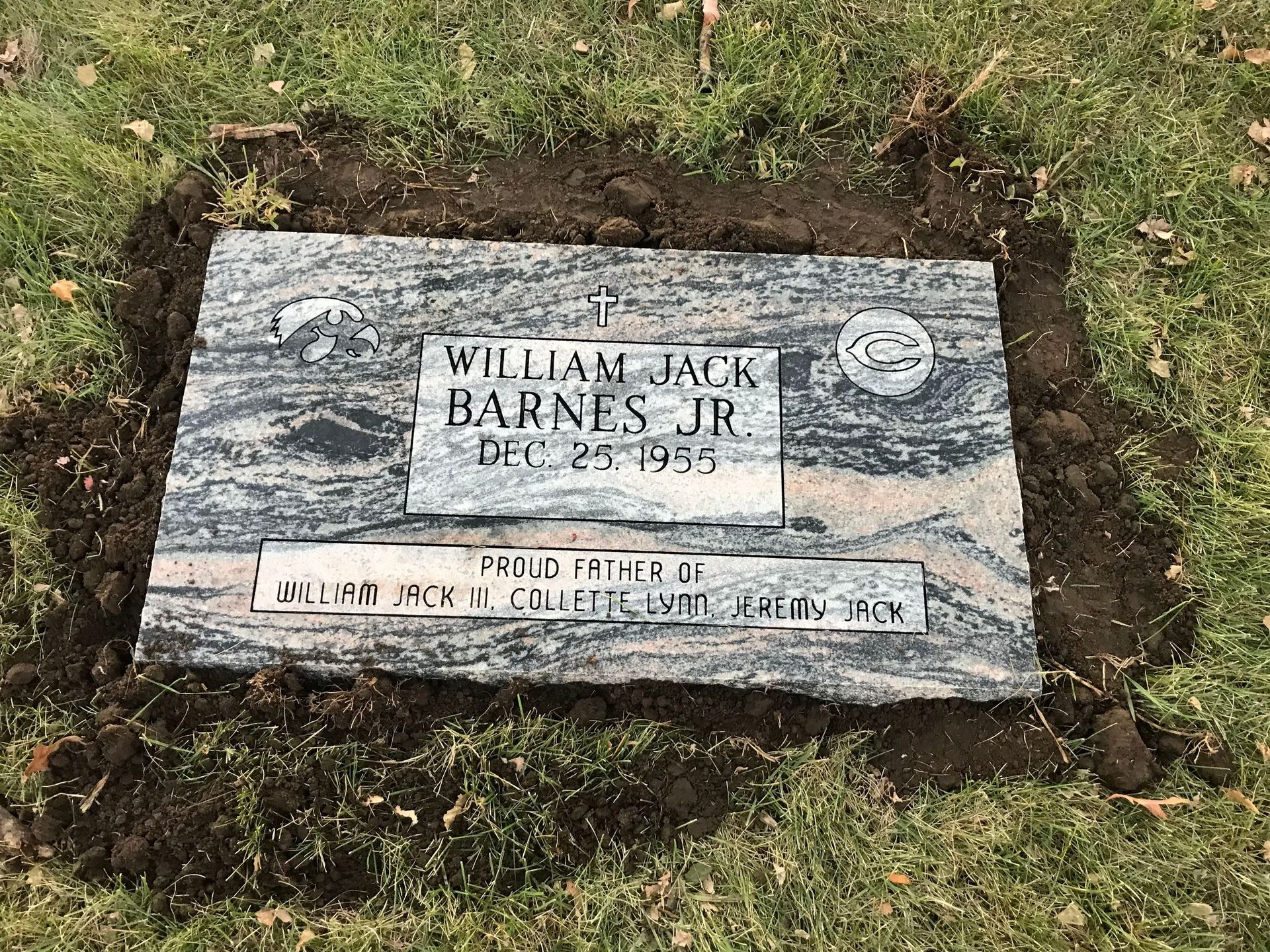 A gravestone is sitting in the grass in a cemetery