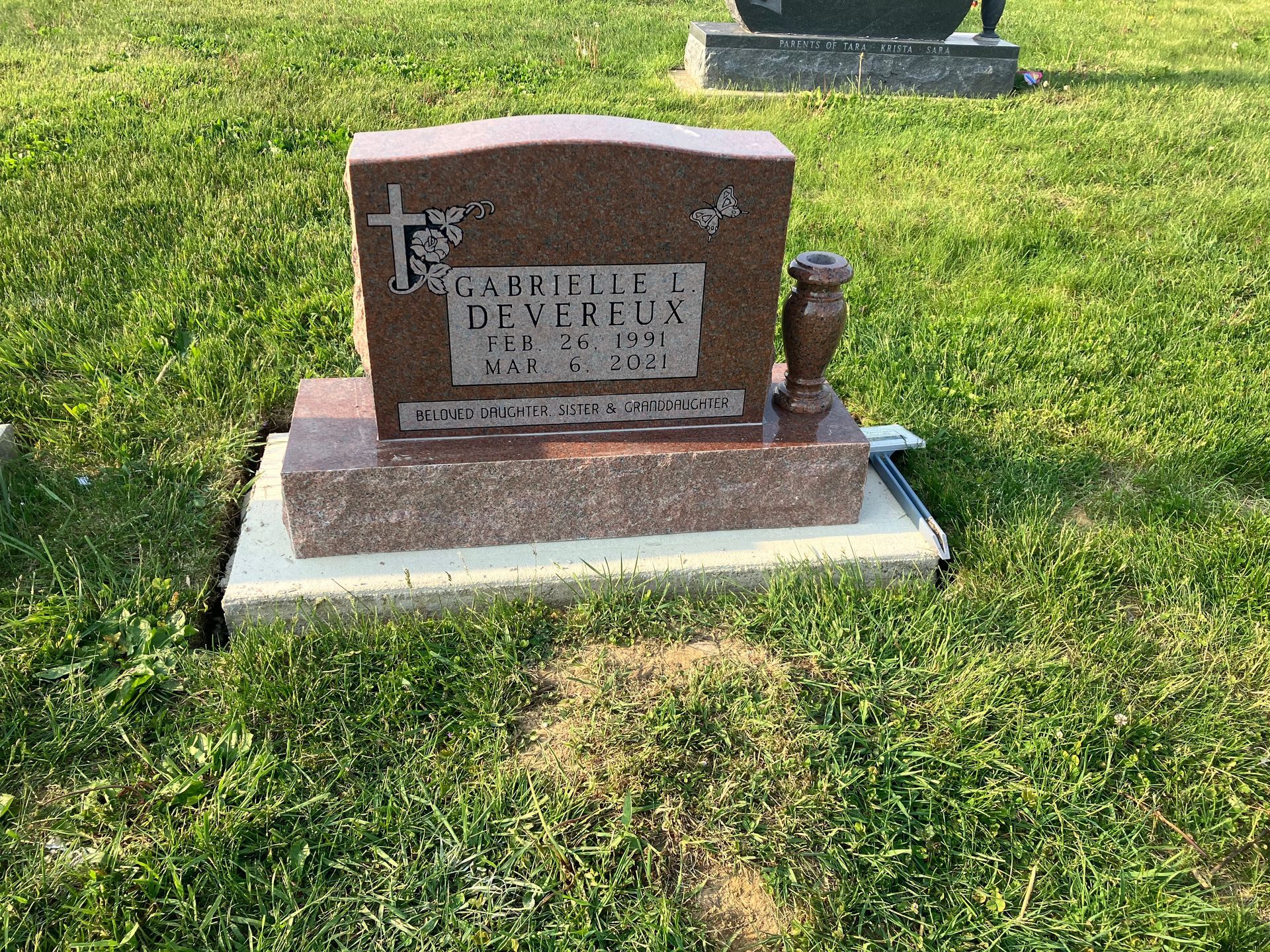 A grave in a cemetery with a cross on it