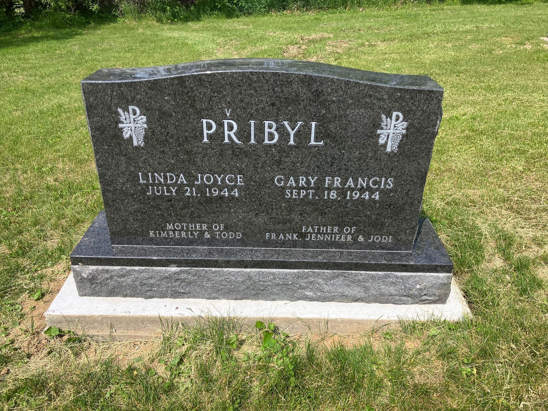 A black gravestone in a cemetery with the name Pribyl on it