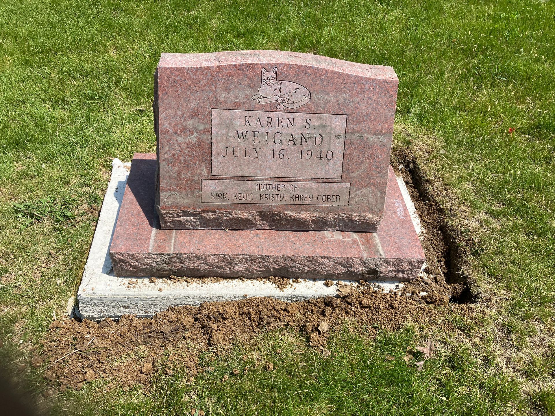 A gravestone is sitting in the middle of a grassy field