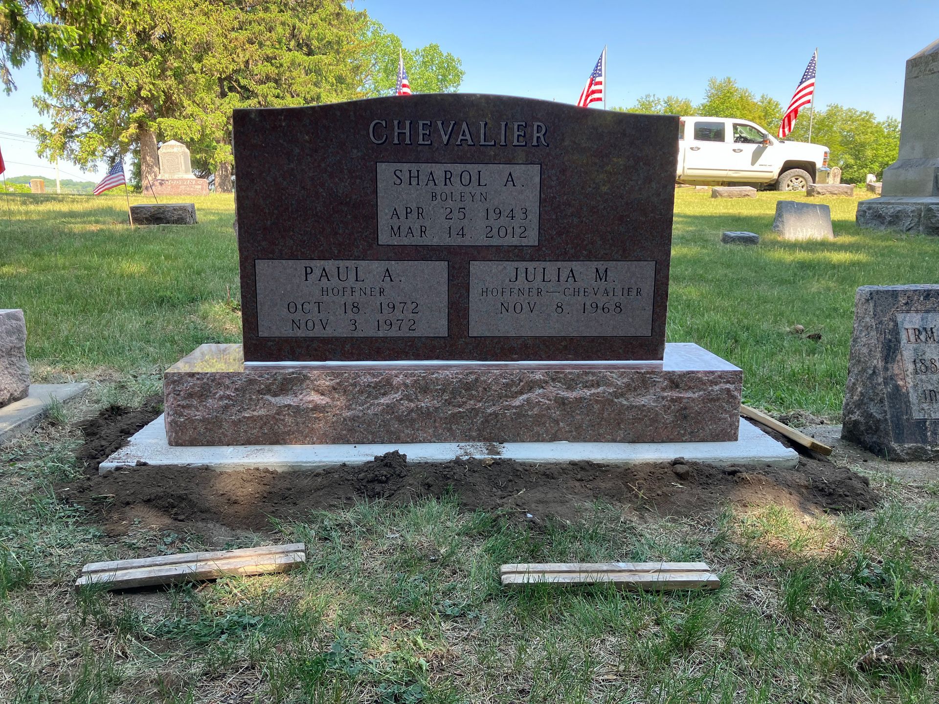 A grave in a cemetery with a truck parked in the background