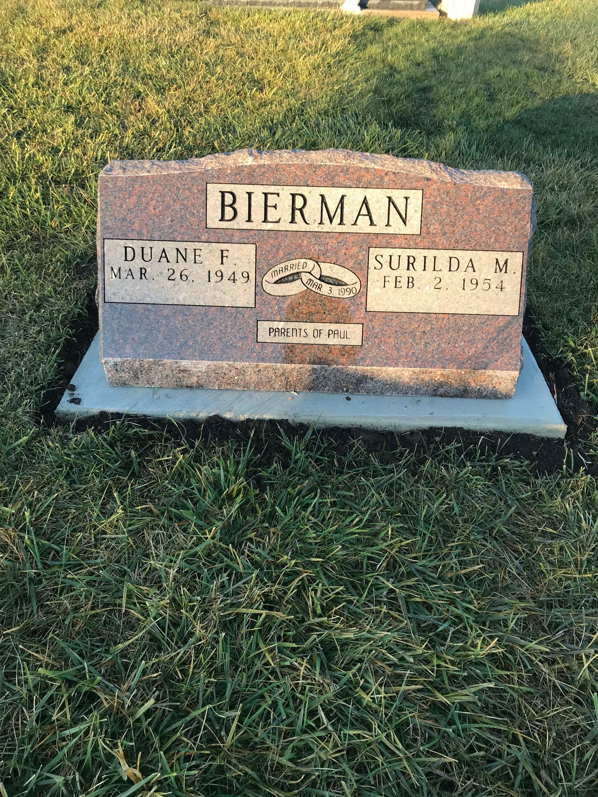 A gravestone in a cemetery sitting on top of a lush green field