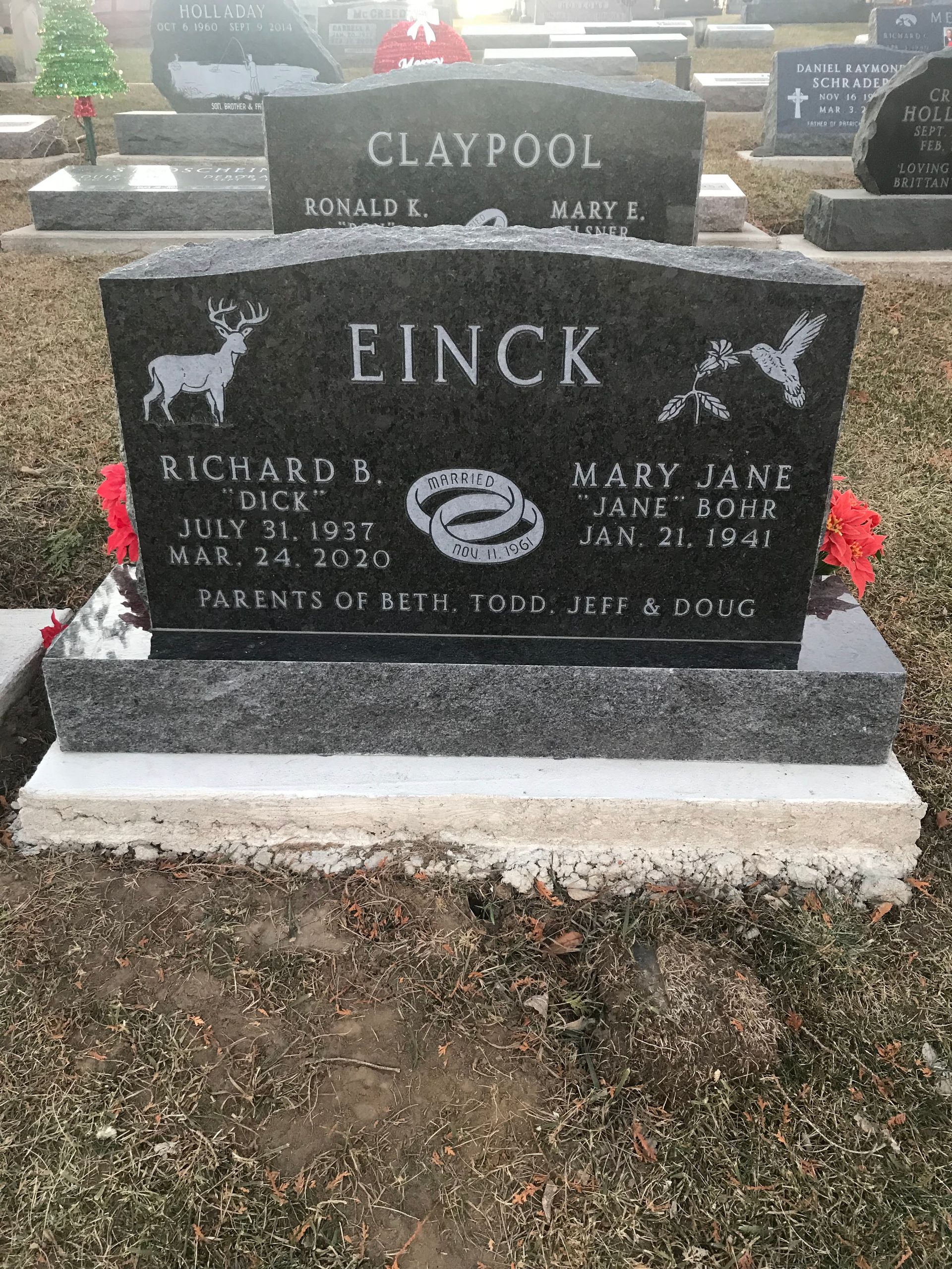 A black gravestone in a cemetery with flowers on it