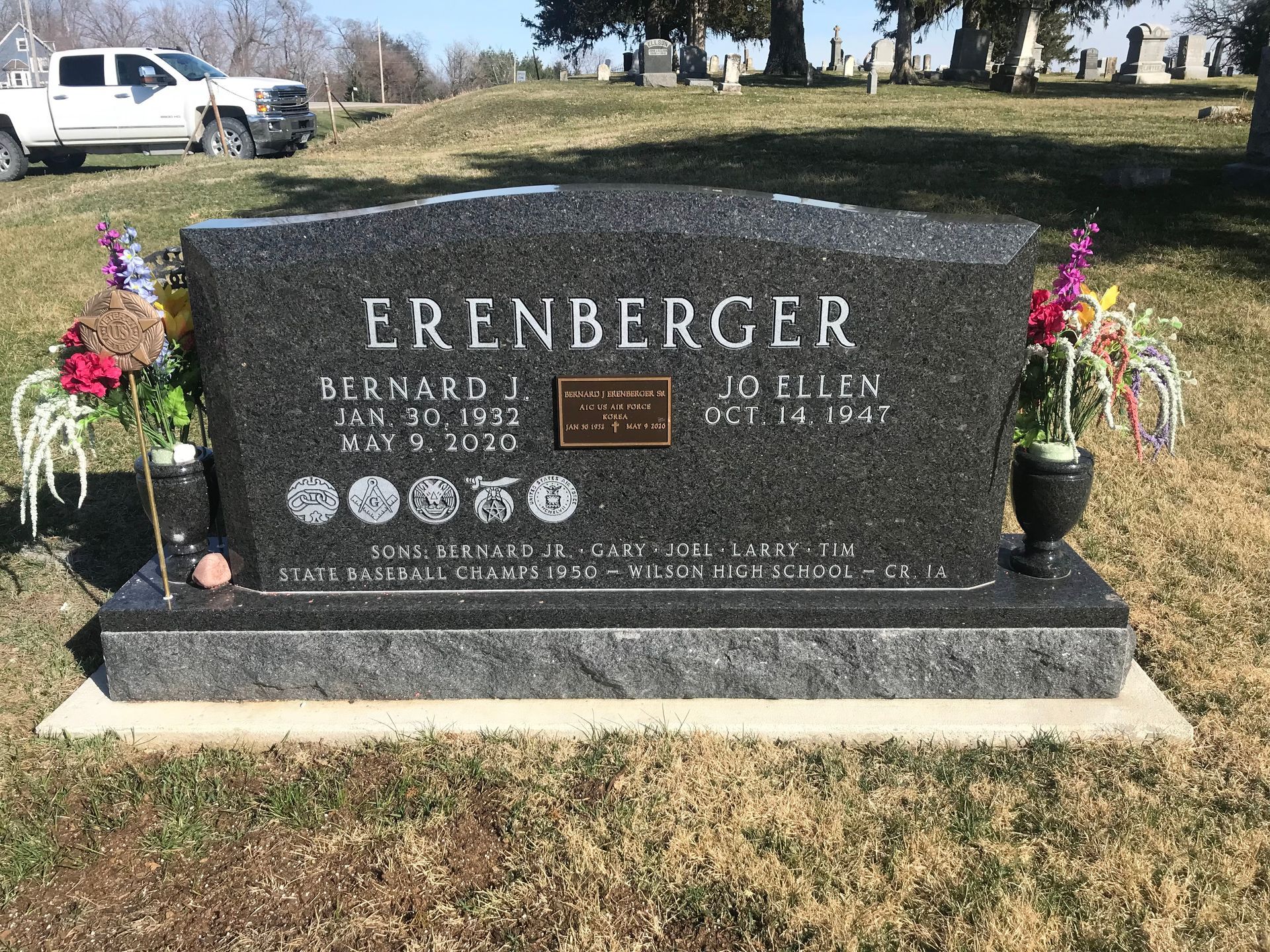 A black gravestone in a cemetery with flowers on it