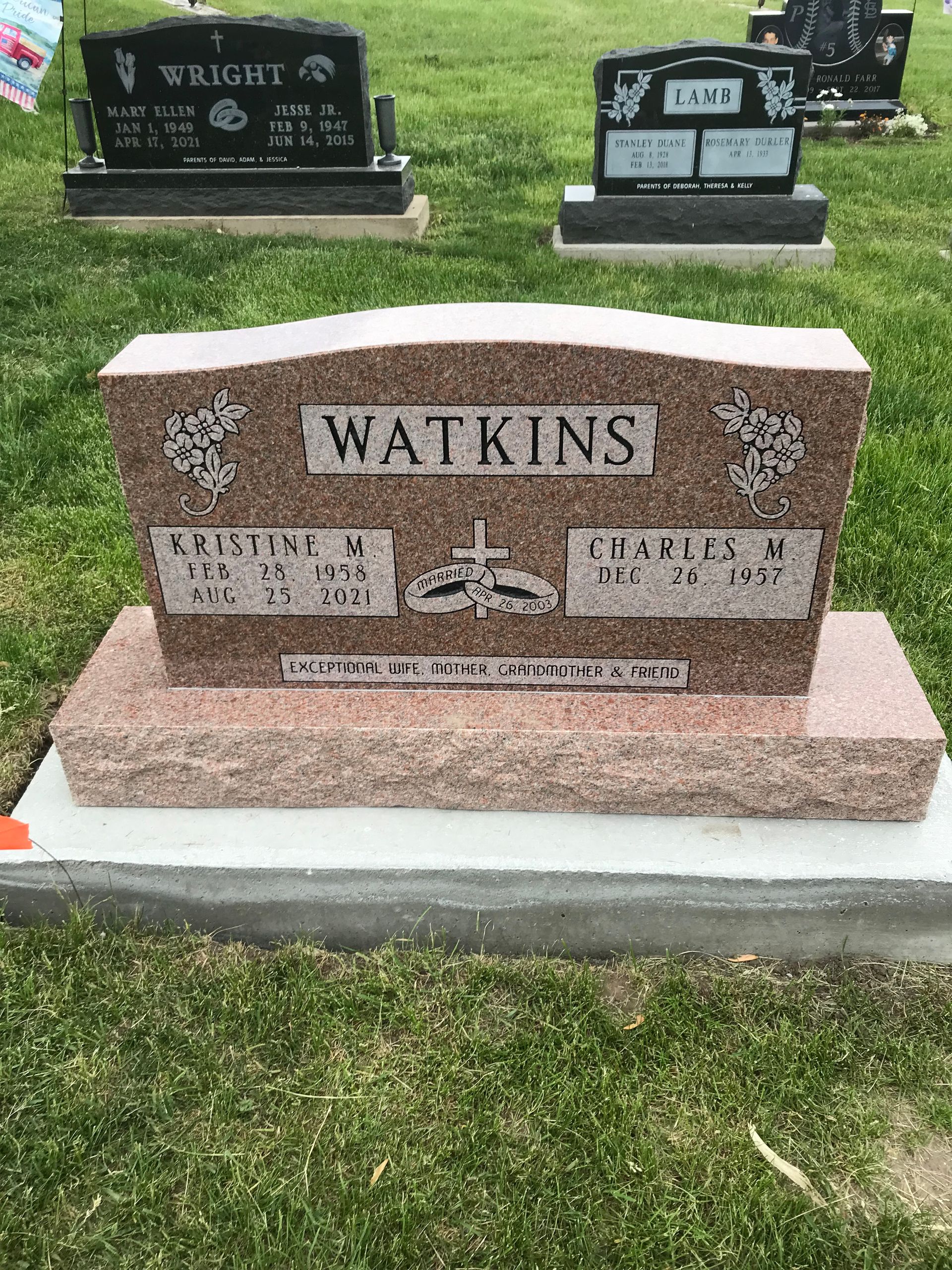 A gravestone for Watkins is in a cemetery with other graves