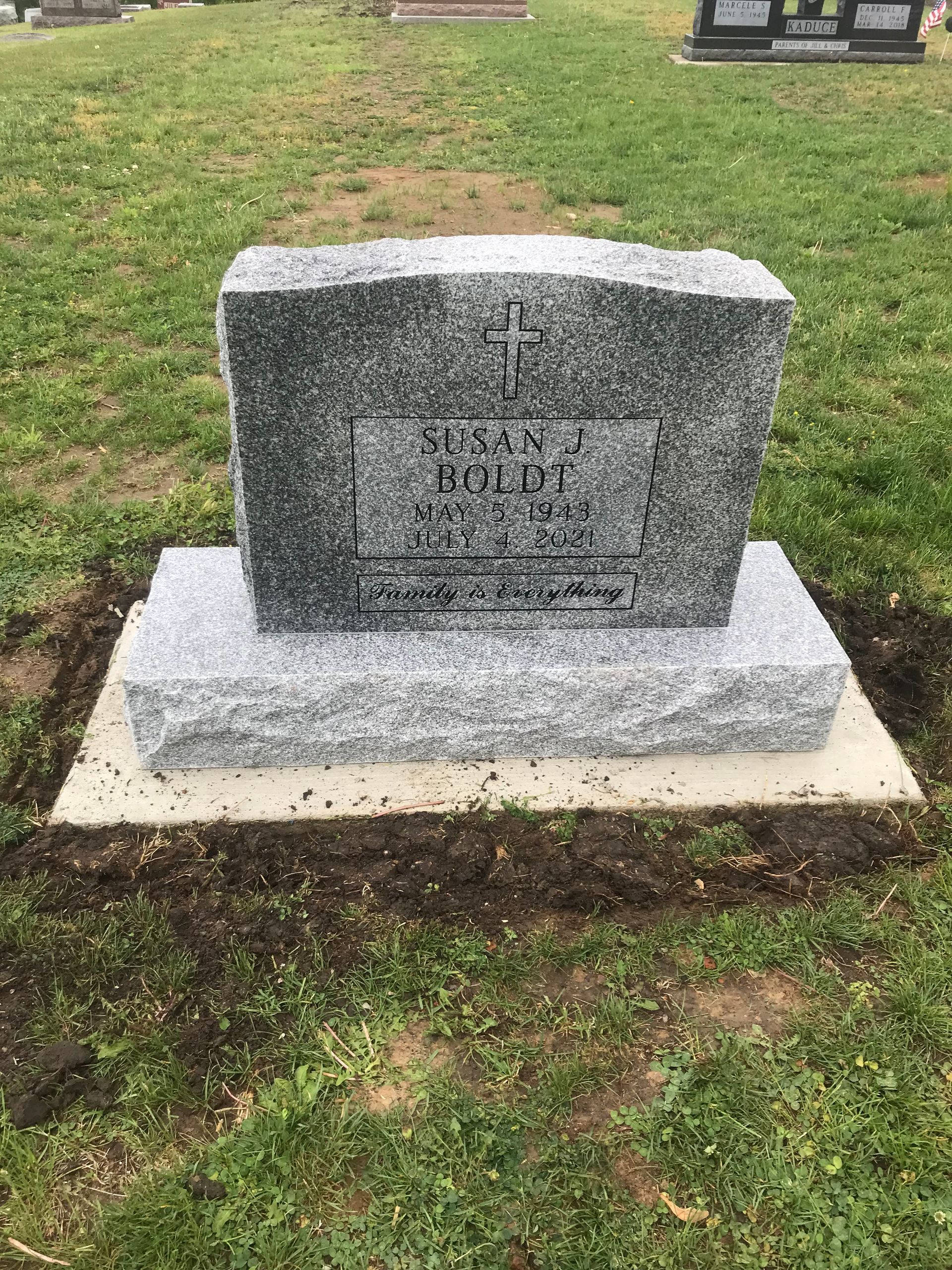 A gravestone is sitting in the middle of a grassy field