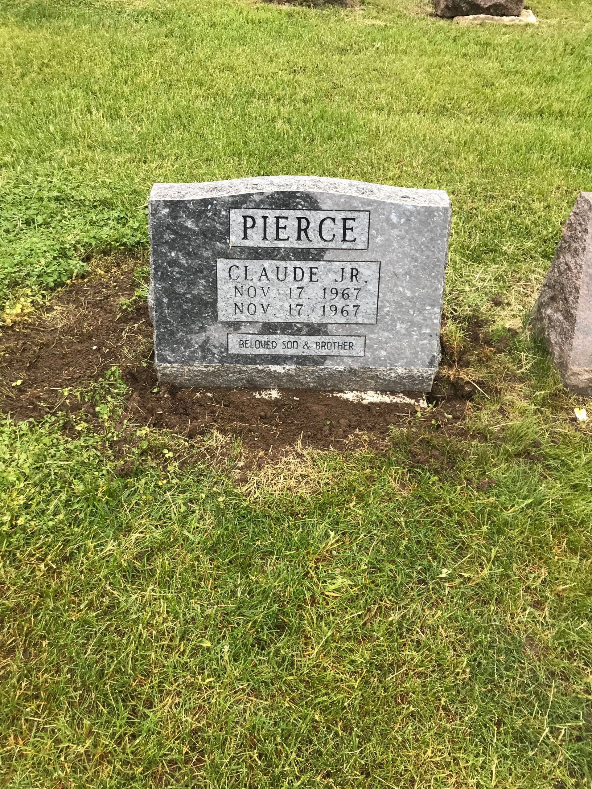 A gravestone in a cemetery with a lot of grass around it
