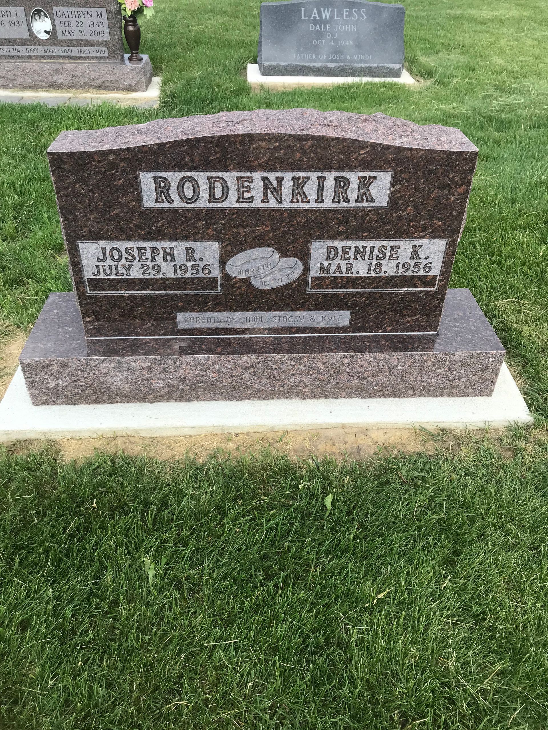 A gravestone in a cemetery with other graves in the background.