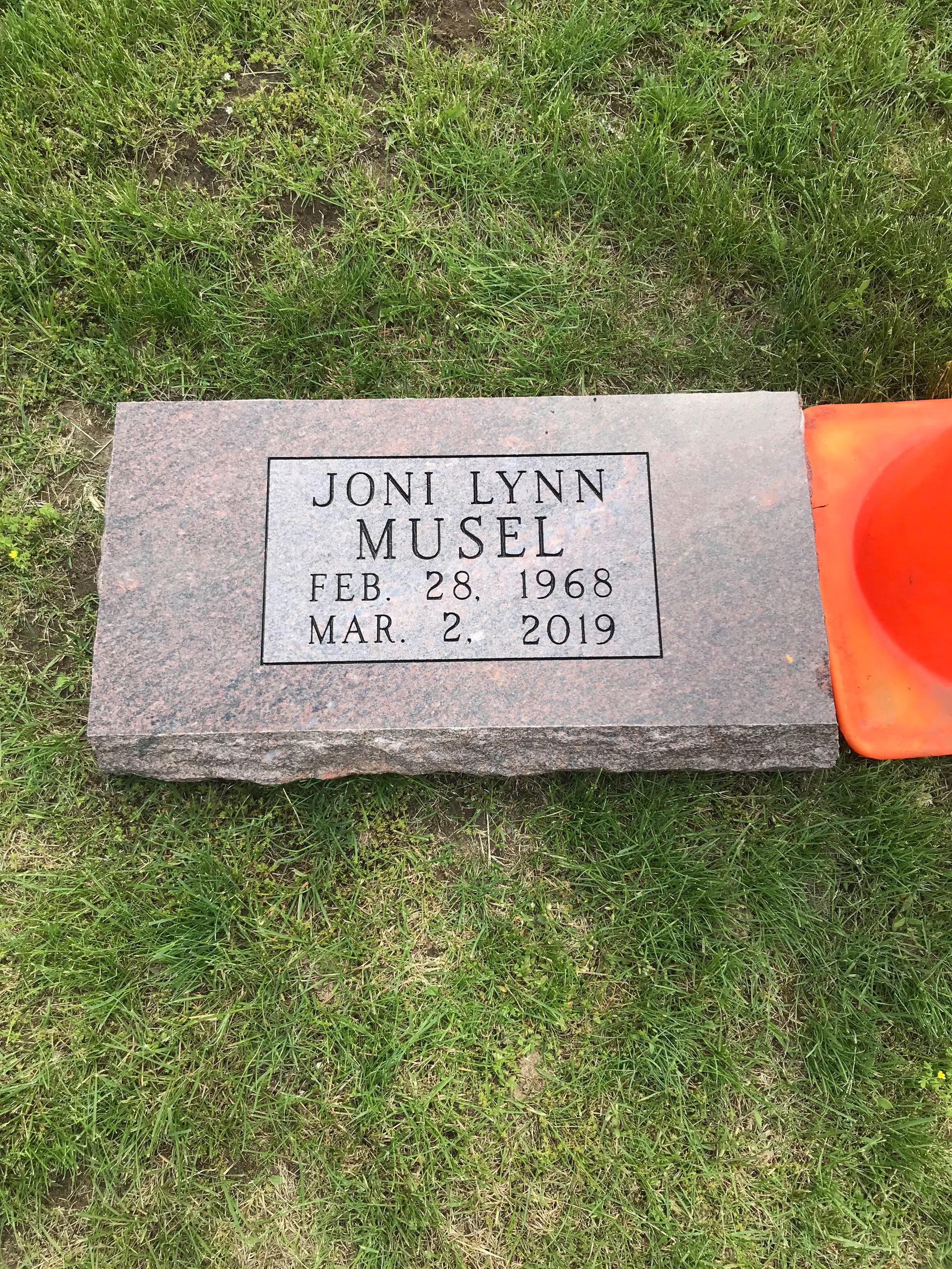 A gravestone in a cemetery with a cone on top of it.