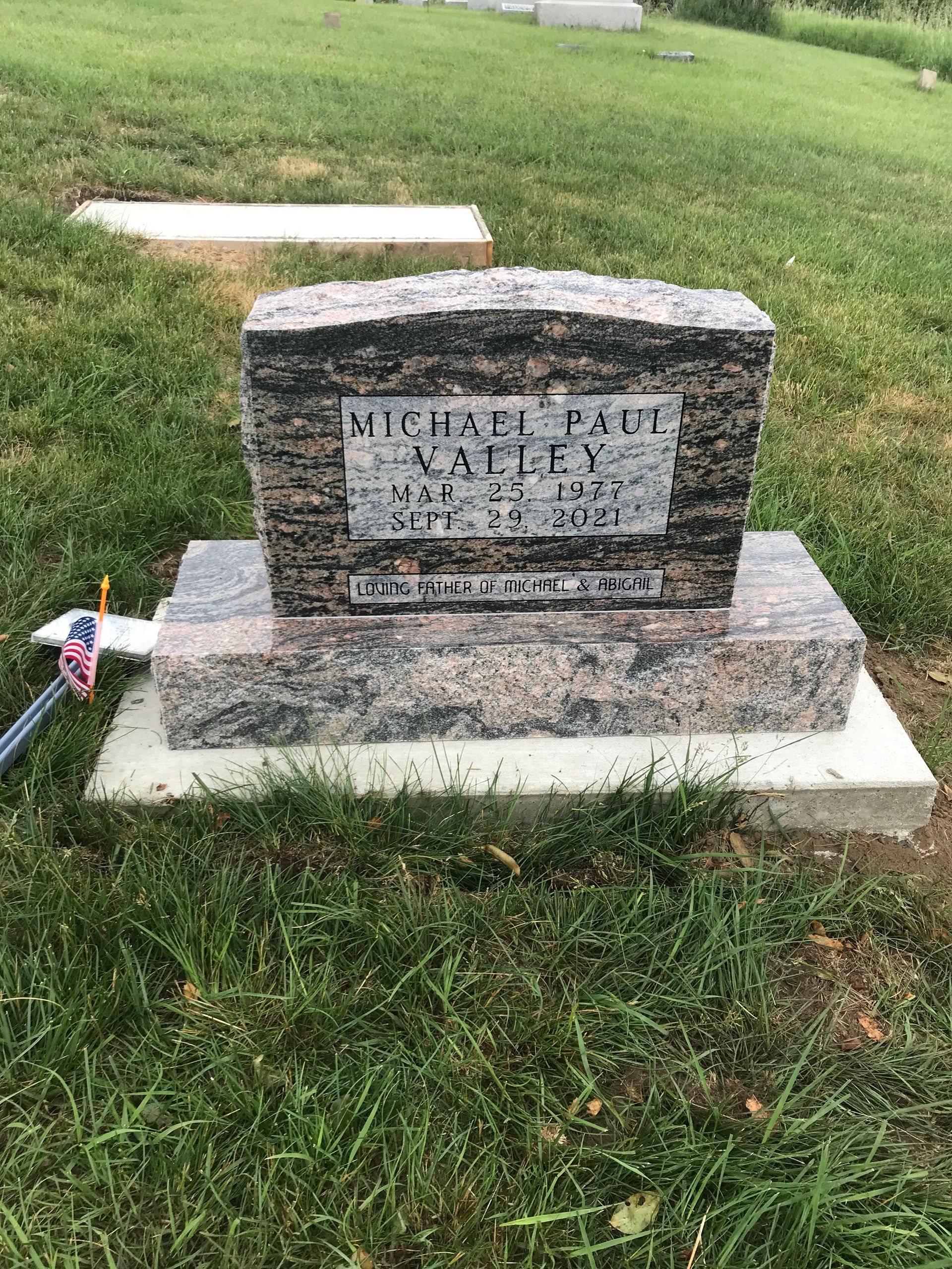 A gravestone in a cemetery with a flag on it.