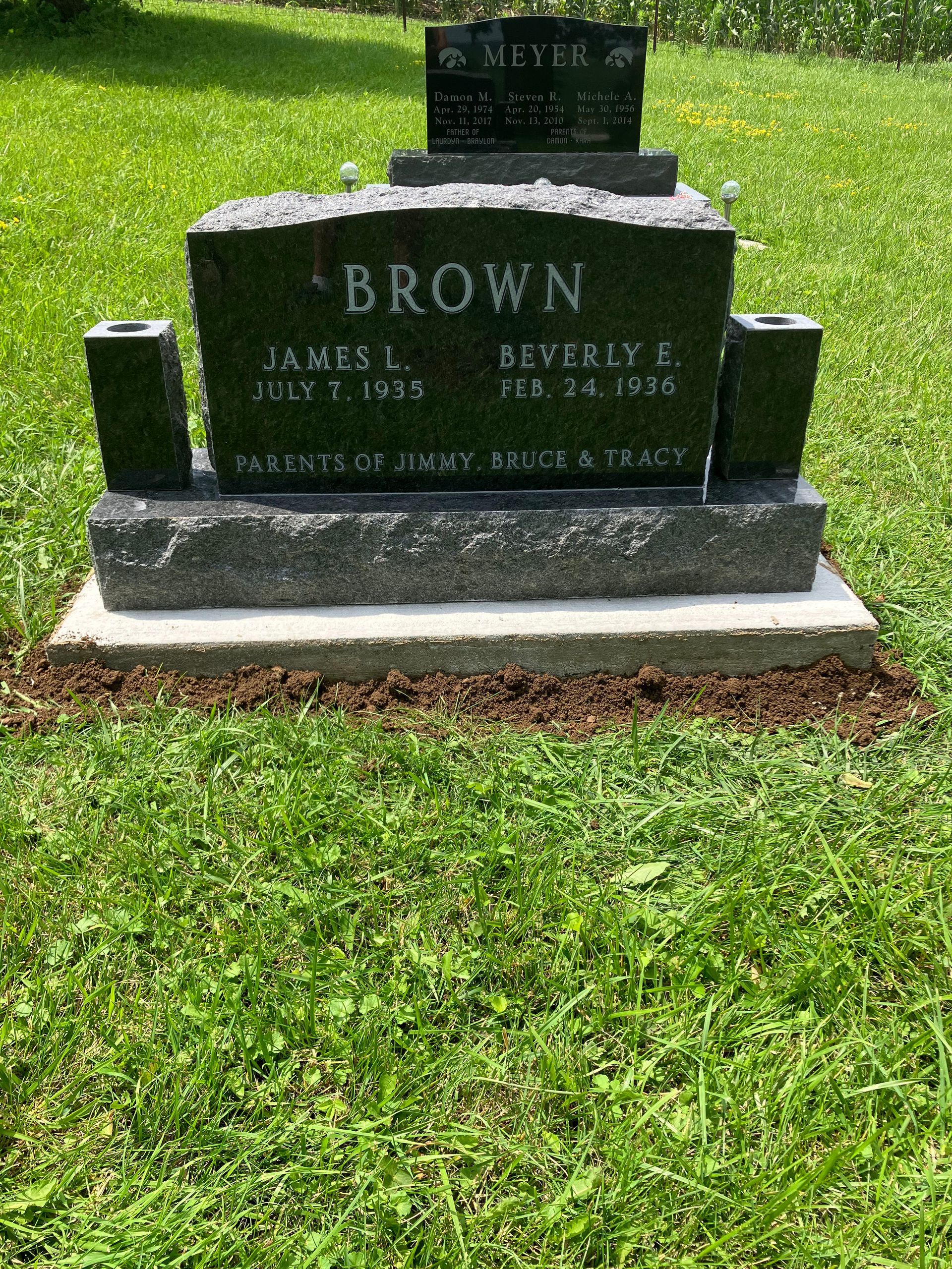 A gravestone for Brown is sitting in the middle of a lush green field.