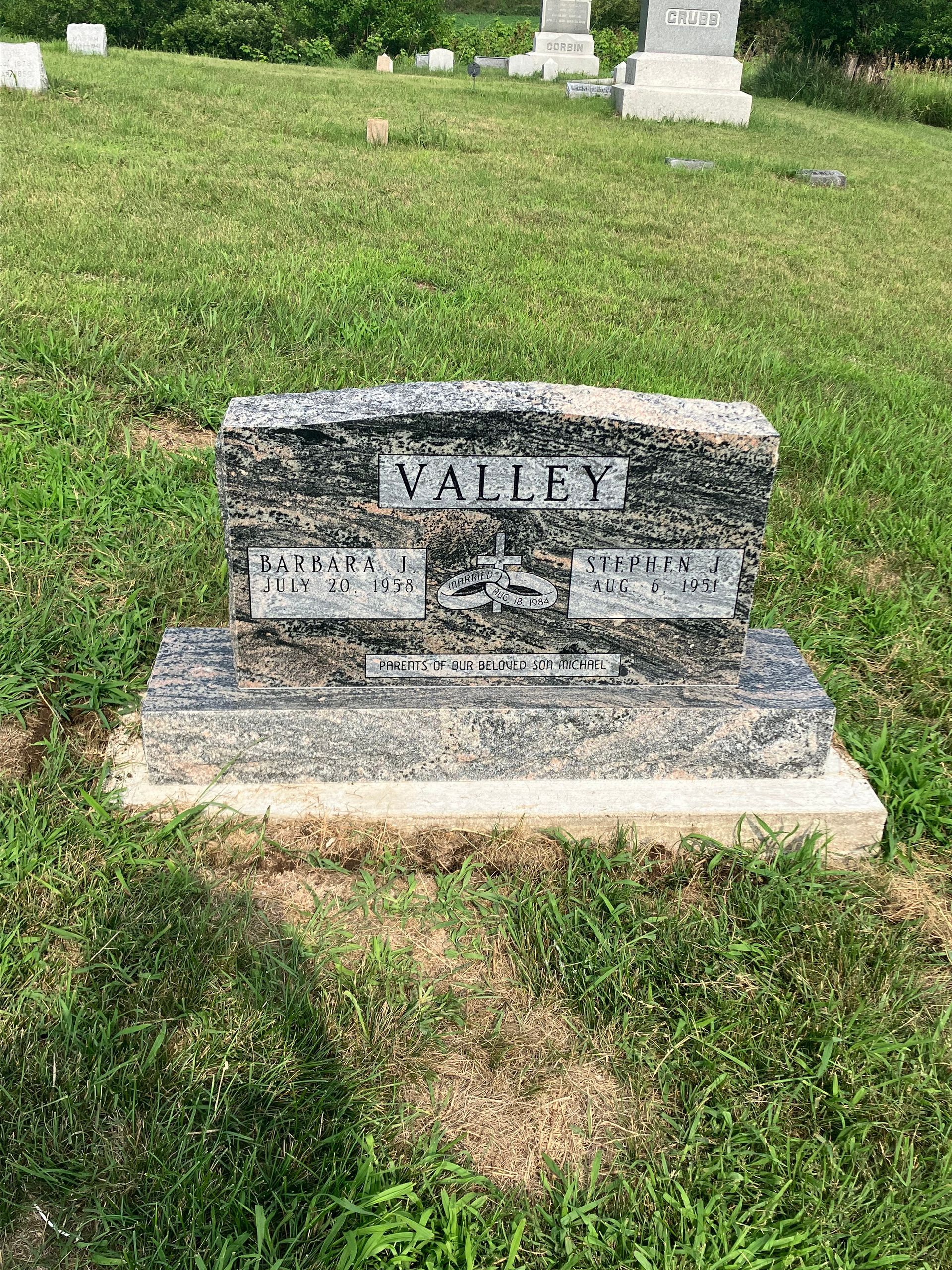 A gravestone in a cemetery surrounded by grass.