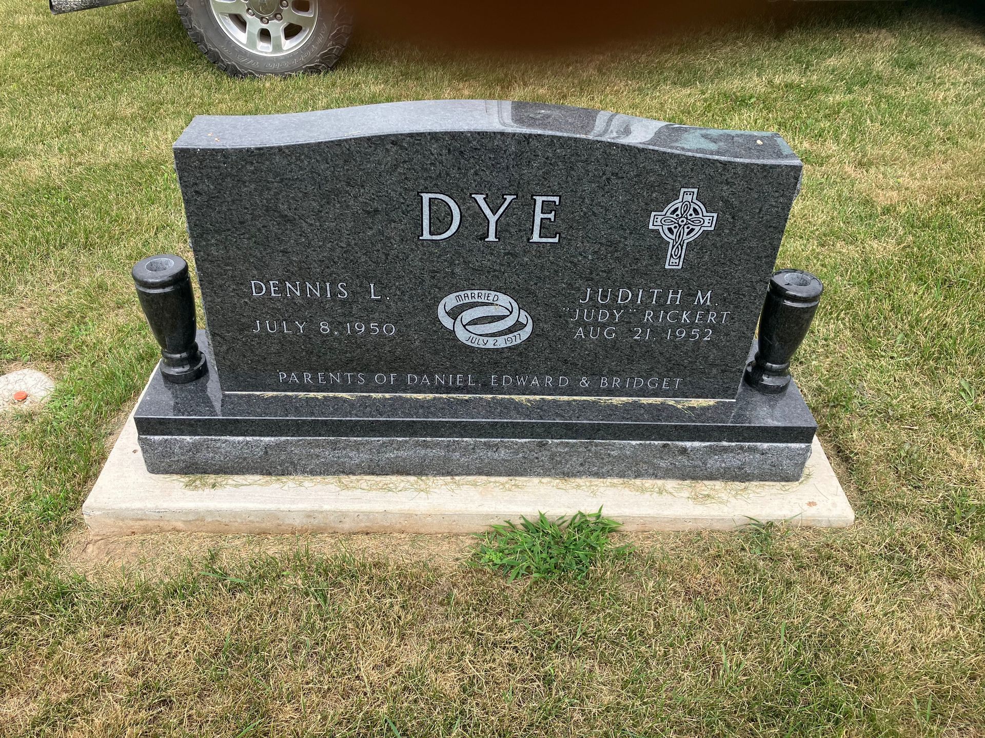 A gravestone for Dye is sitting in the grass in a cemetery.