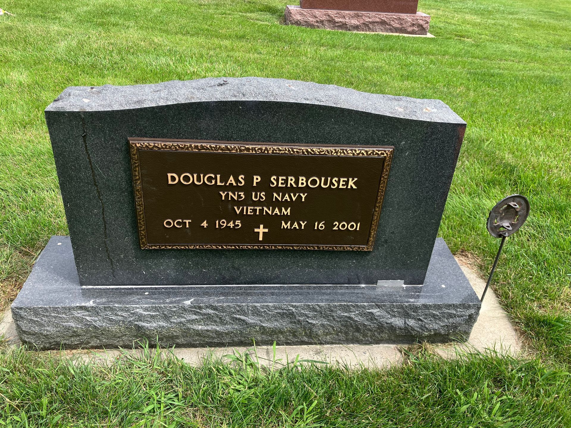A gravestone for Douglas Serbousek in a cemetery.