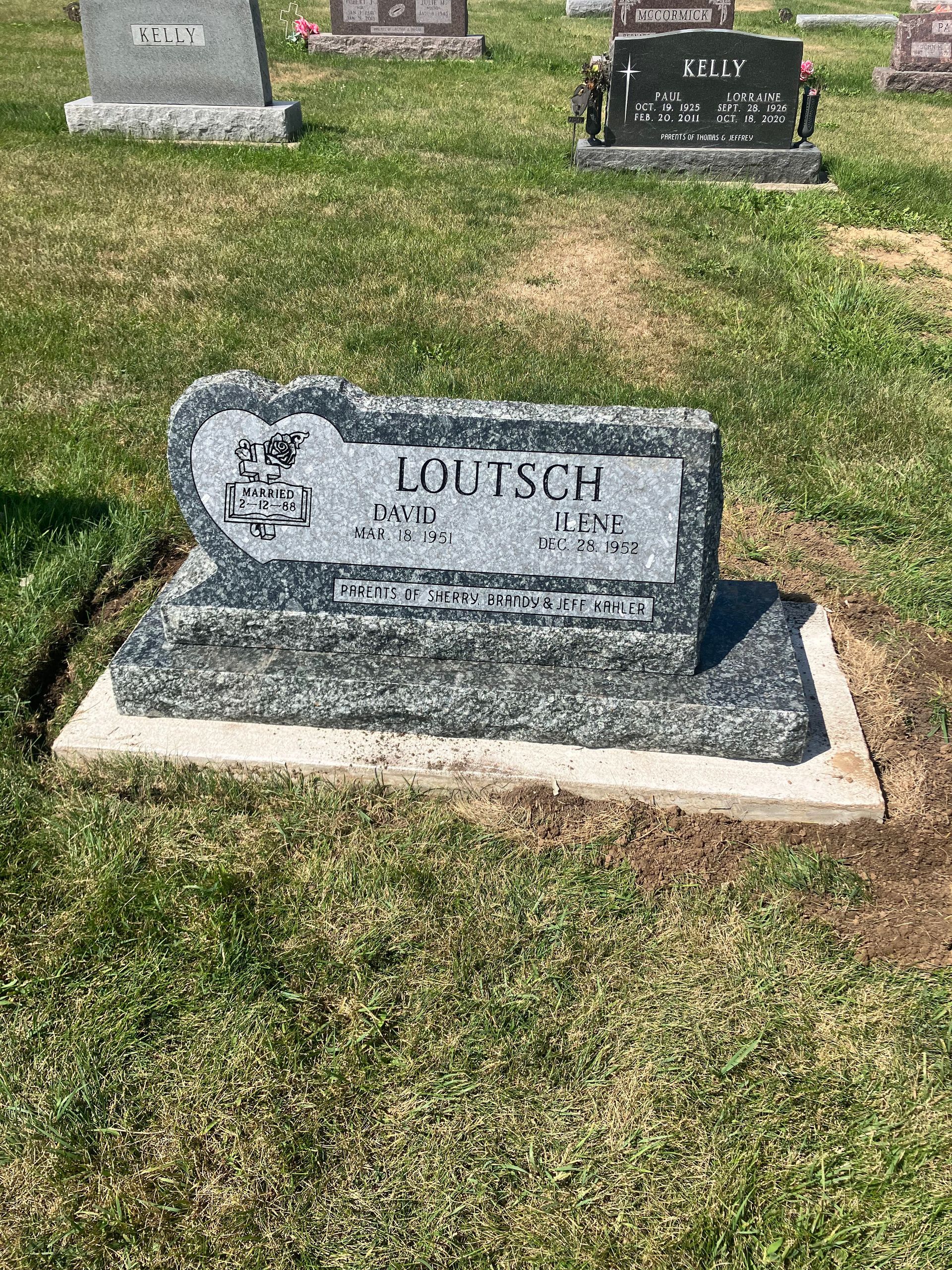 A grave in a cemetery with a bench in the grass.