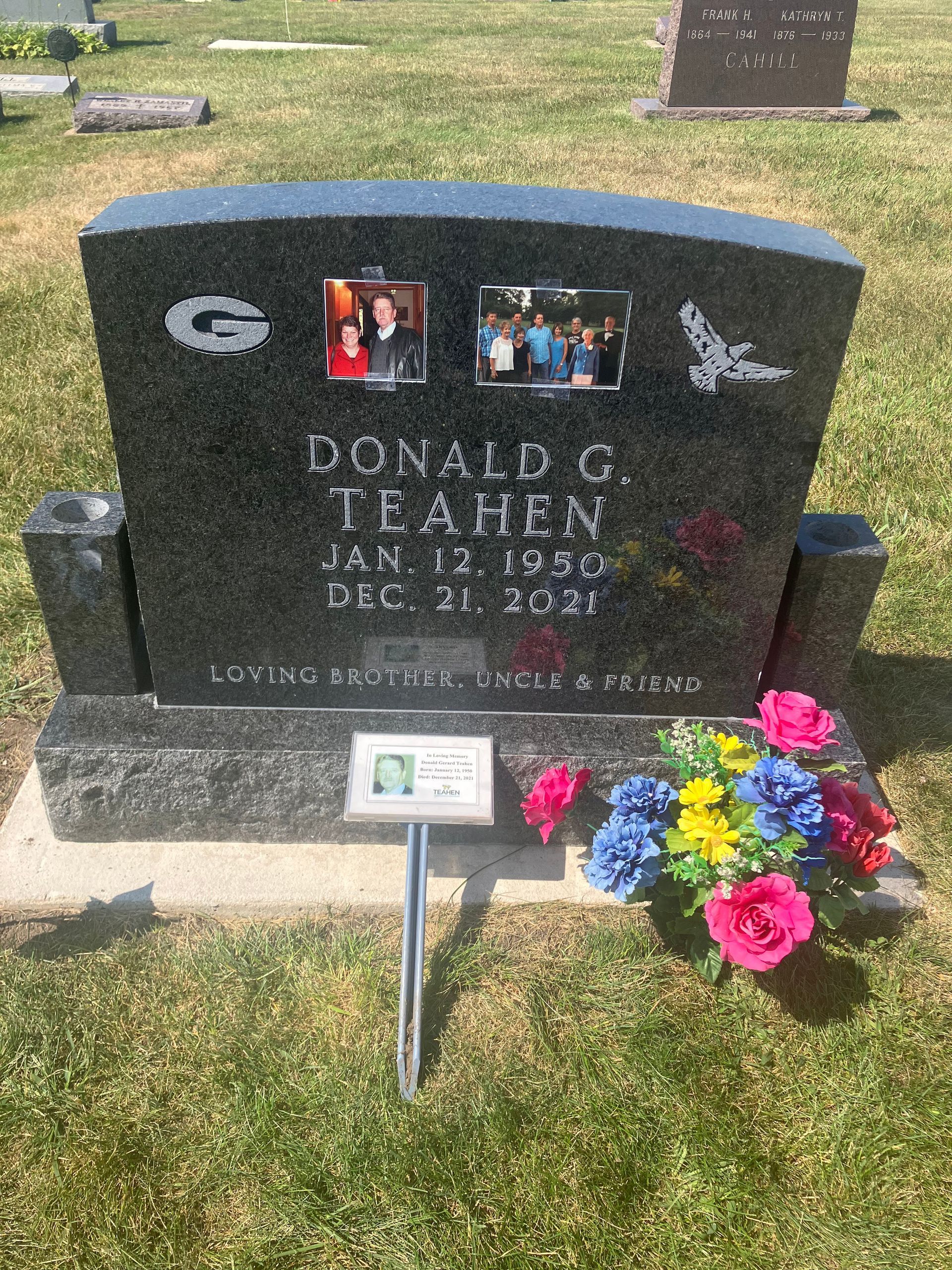 A gravestone in a cemetery with flowers and pictures on it.