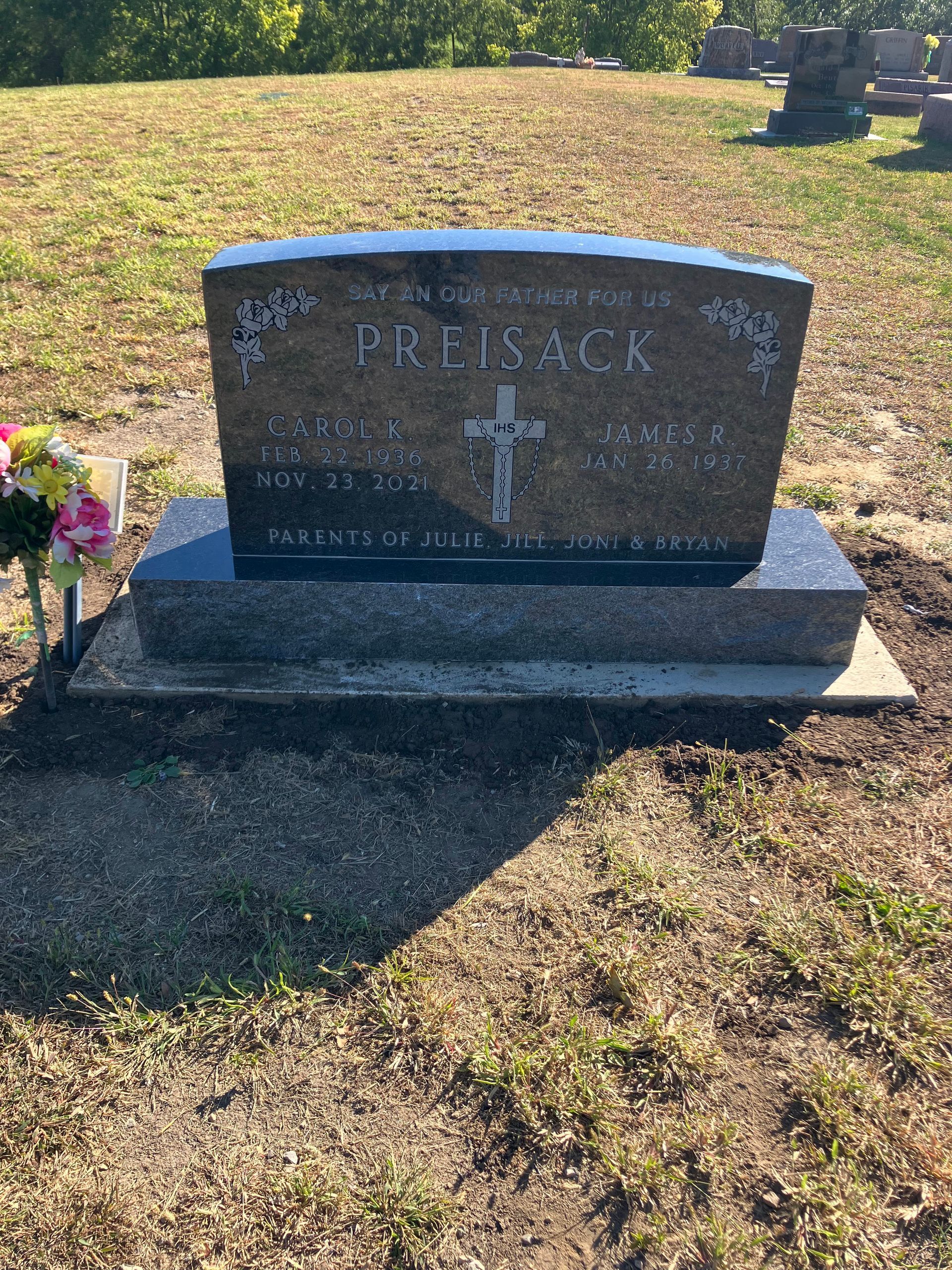 A gravestone in a cemetery with flowers on it.