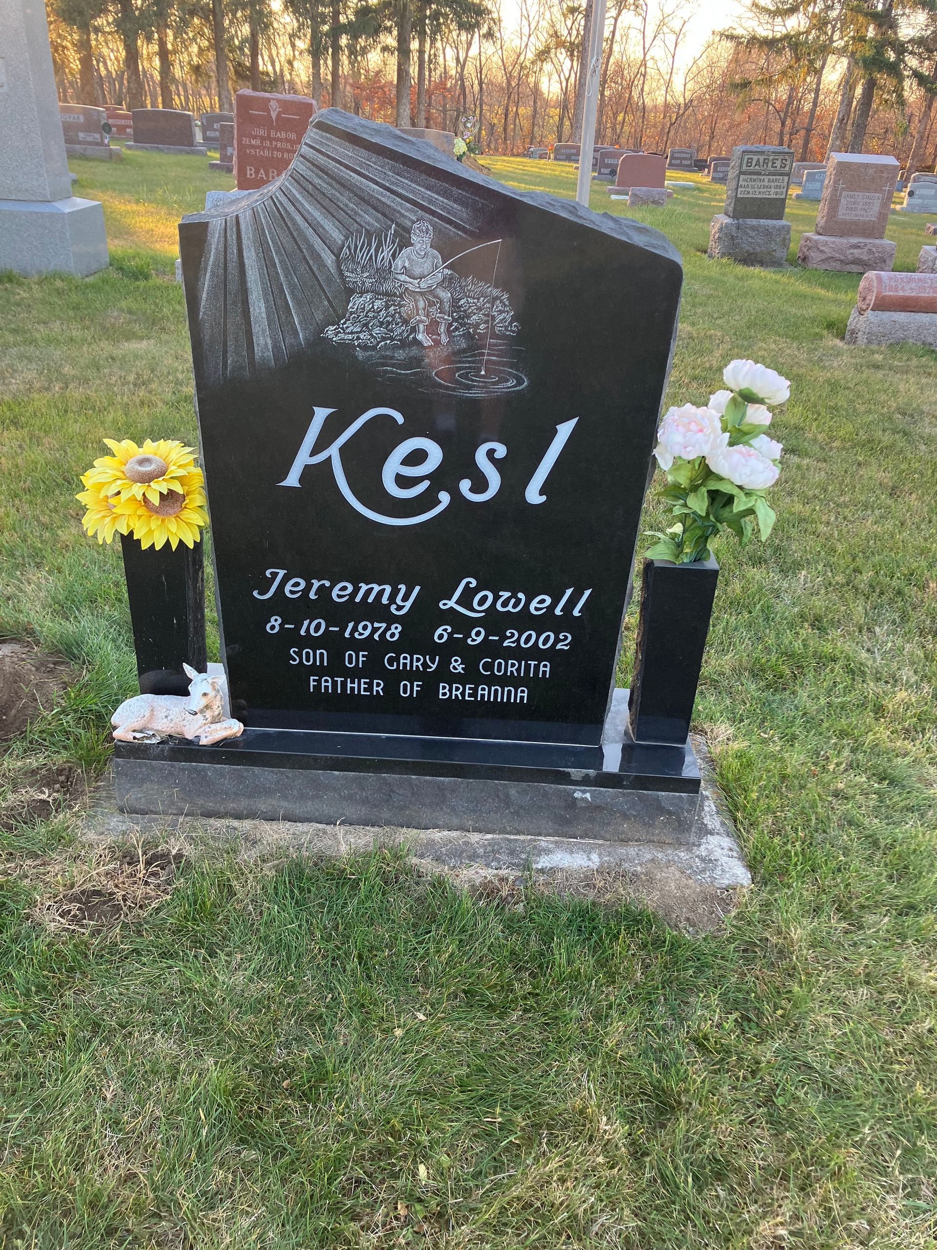 A black gravestone with flowers in vases in a cemetery