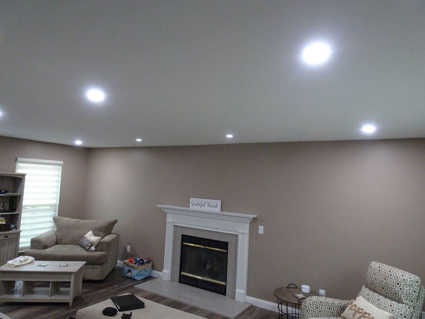 Living room with a fireplace, beige sofa, coffee table, and recessed ceiling lights
