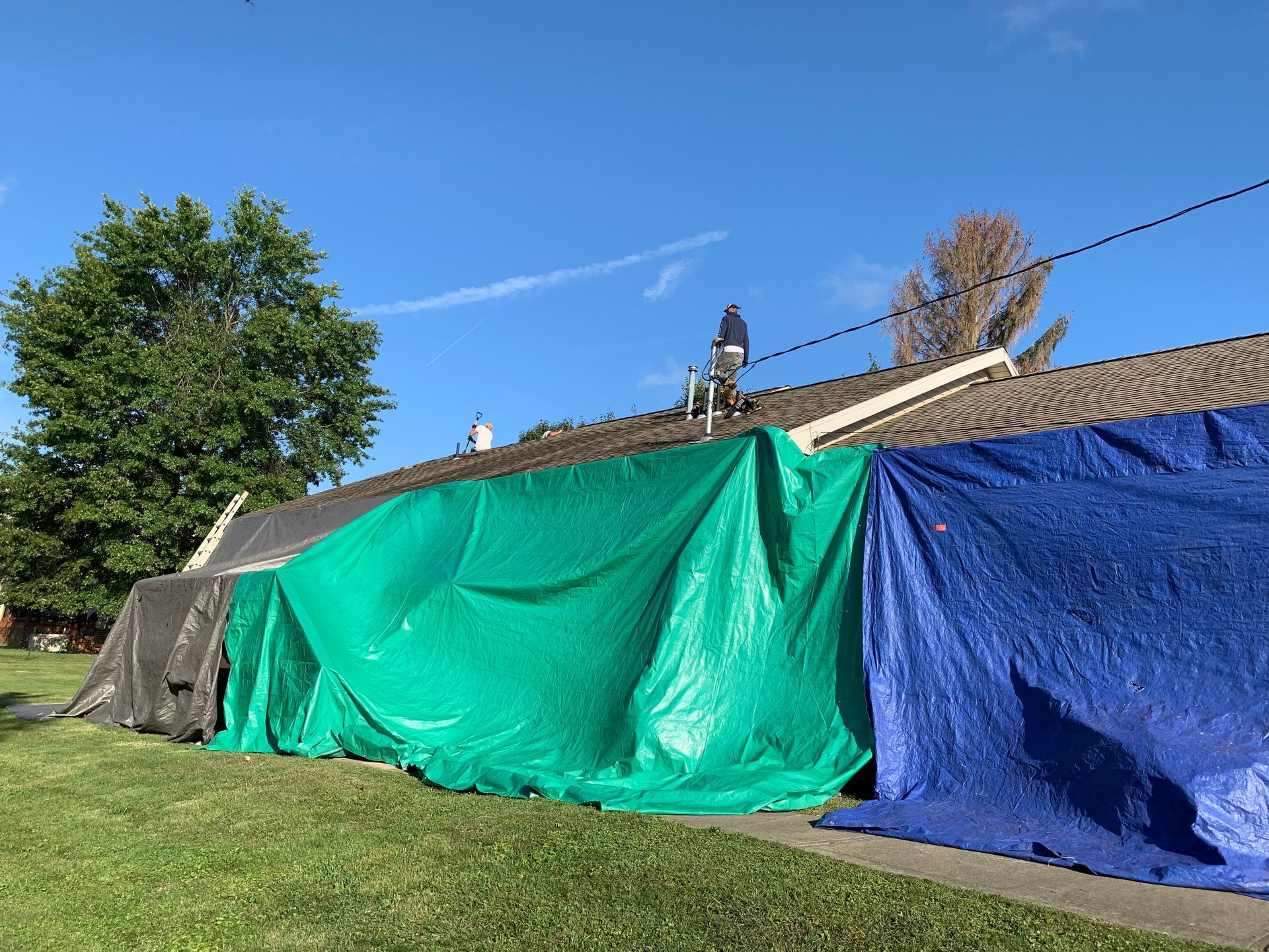A blue tarp is covering the roof of a house.