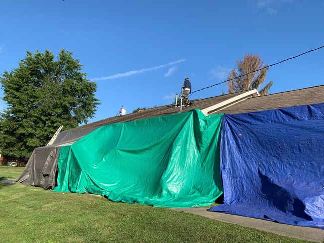 A blue tarp is covering the roof of a house.