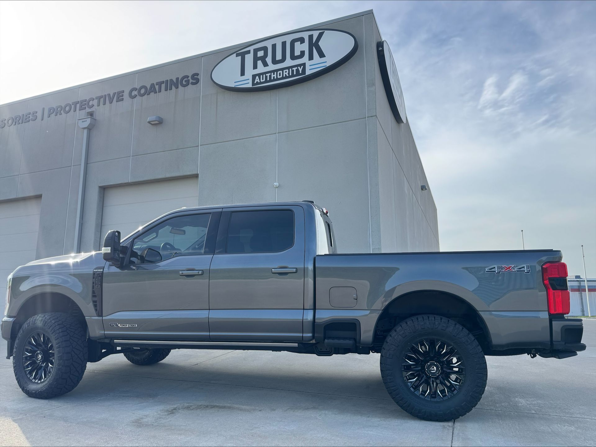 Silver pickup truck parked outside a truck accessories shop.