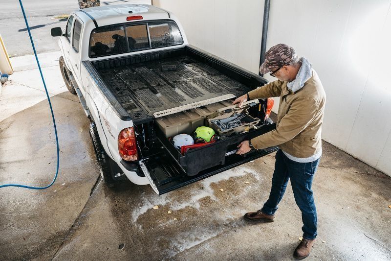 Man loading tools into a black pickup truck bed at a car wash