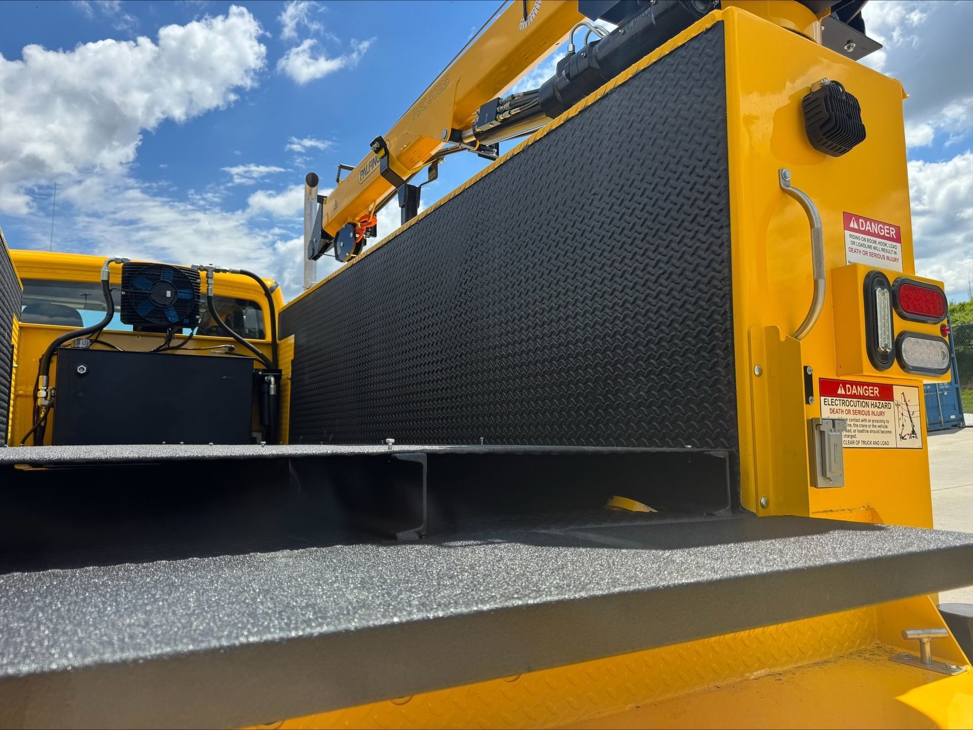 Yellow construction machinery with a black metal attachment under a blue sky.