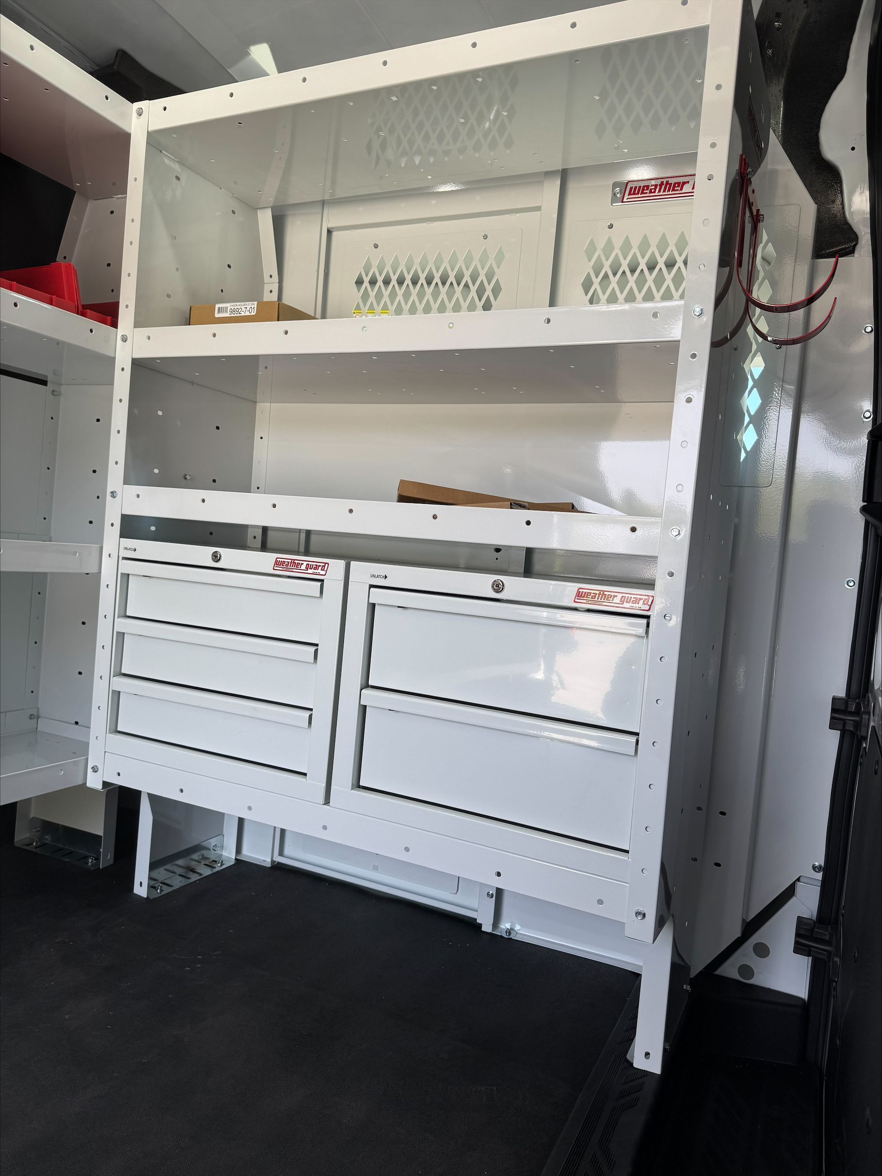 White built-in cabinet with shelves and drawers inside a vehicle or utility space.
