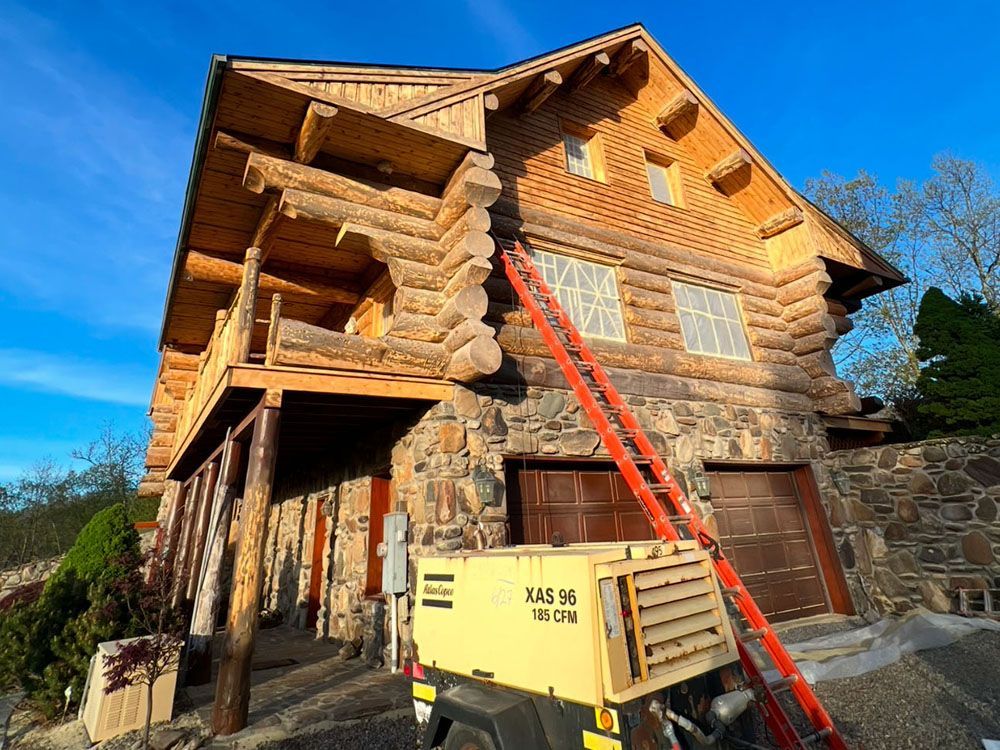 A large log cabin with a ladder in front of it.