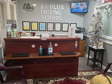 Reception desk in a driving school with certificates on the wall, a Christmas tree, and supplies.