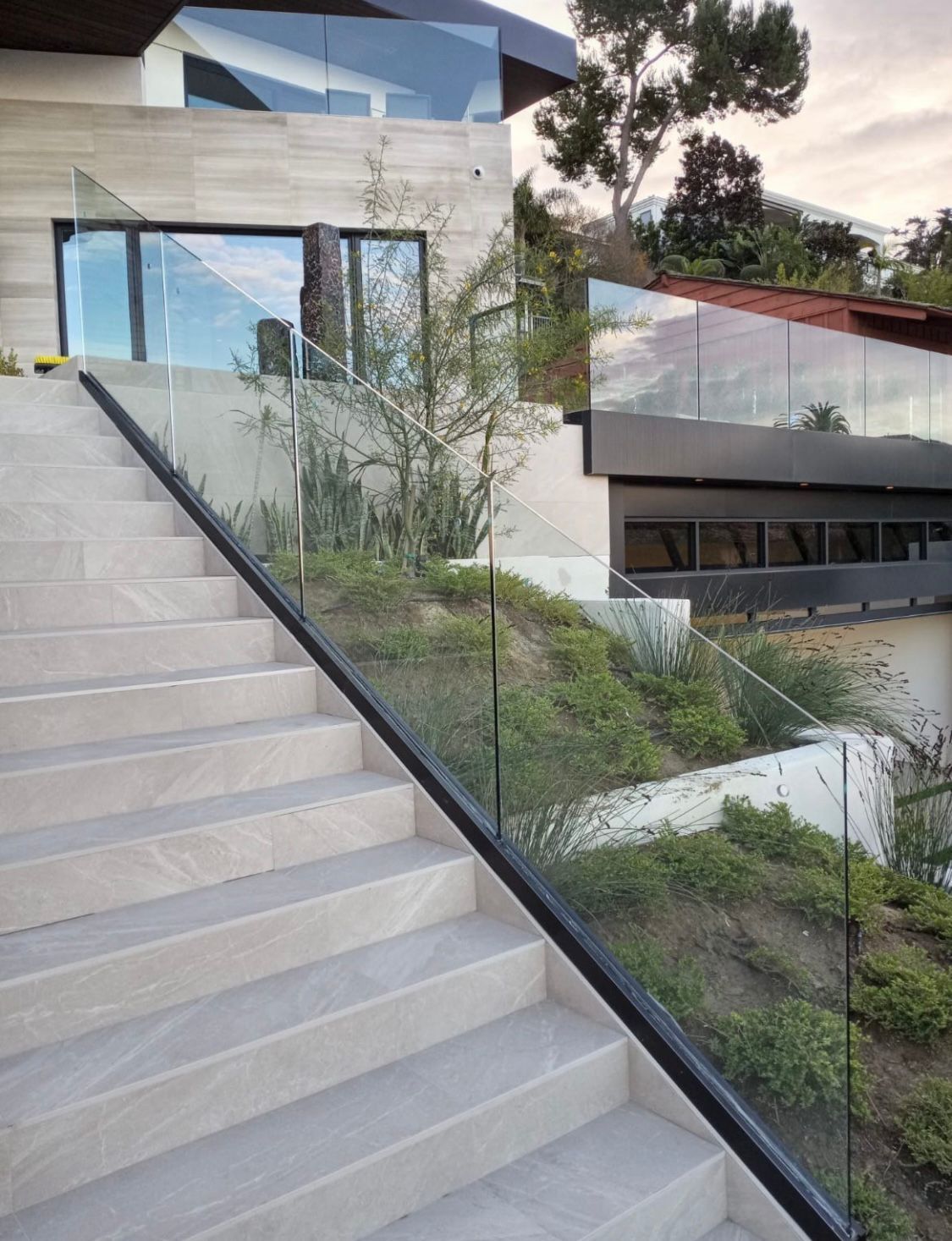 A set of stairs leading up to a house with a glass railing.