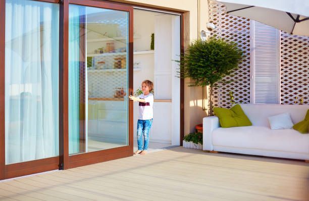 A young boy is standing in front of a sliding glass door.