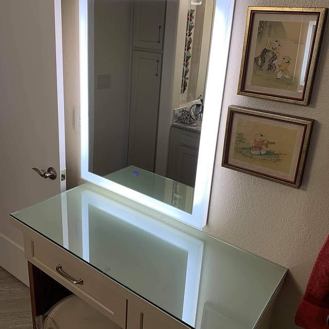 A vanity with a mirror and pictures on the wall