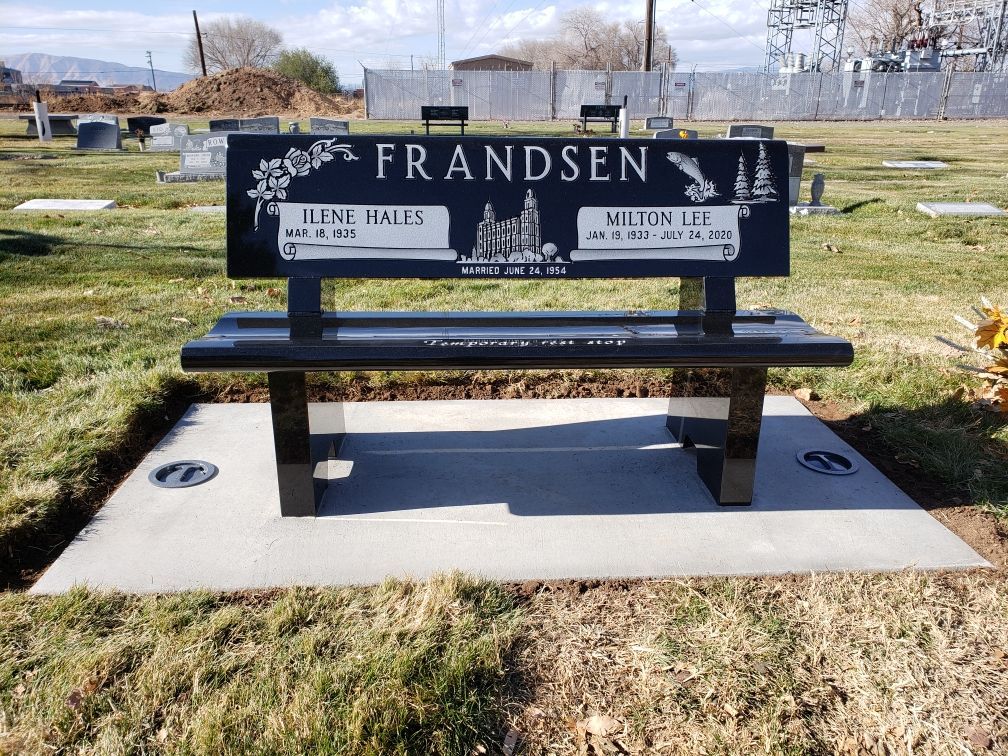 Black granite bench in a cemetery. Engraved with FRANDSEN and names, dates.