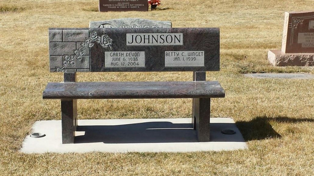 A granite bench with JOHNSON on it, in a cemetery.