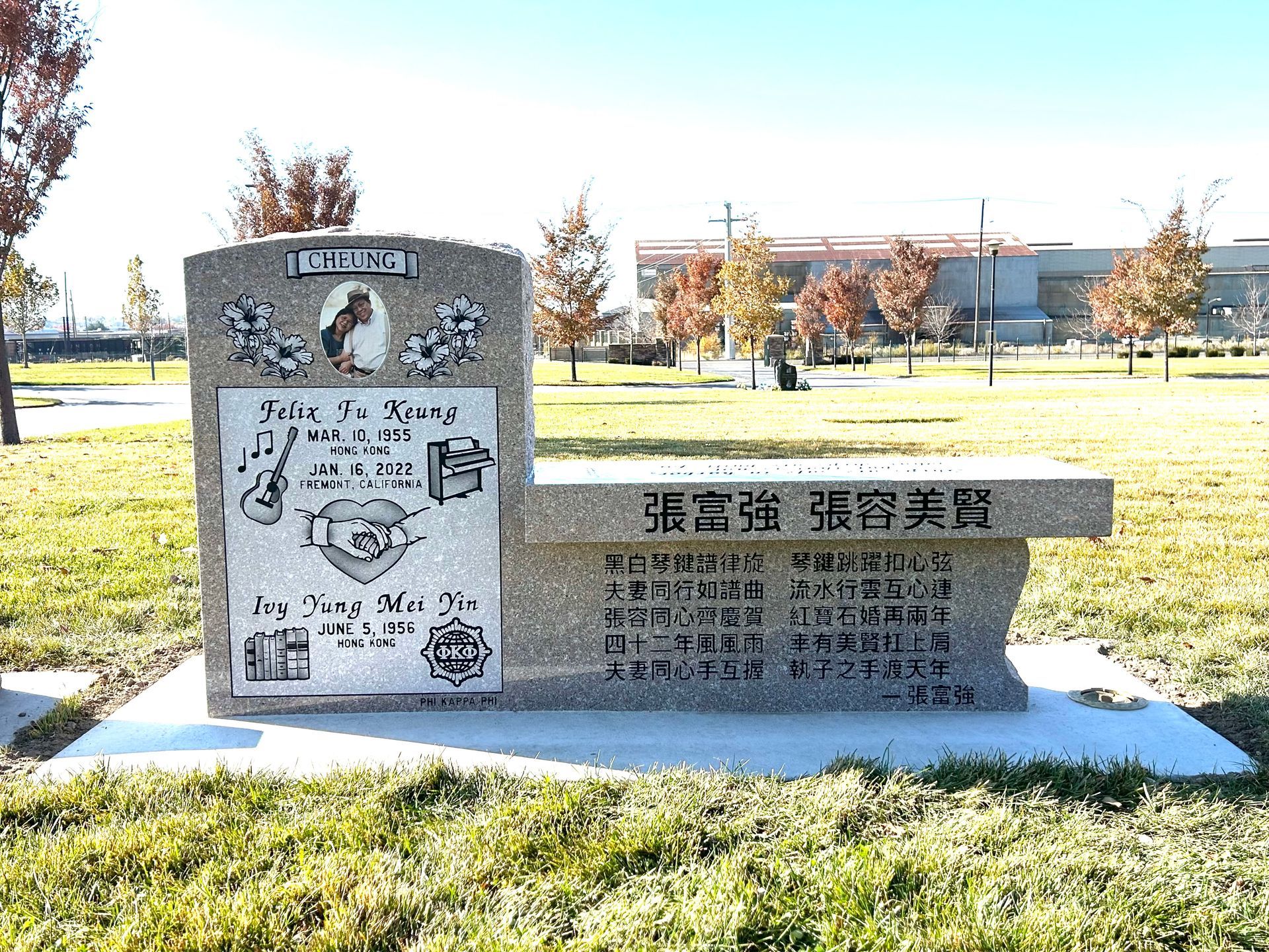 Stone memorial with bench, Chinese inscription, and illustrations in a park setting.