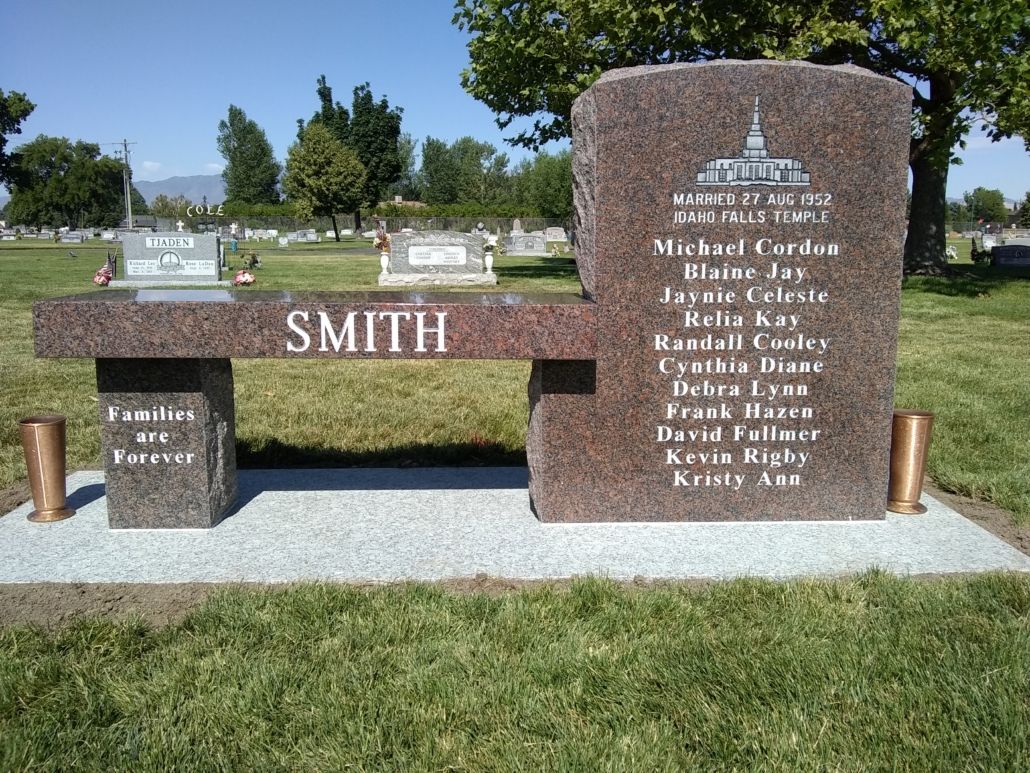 Grave bench with Smith on it, in a cemetery. Names and an illustration of a church are on the headstone.