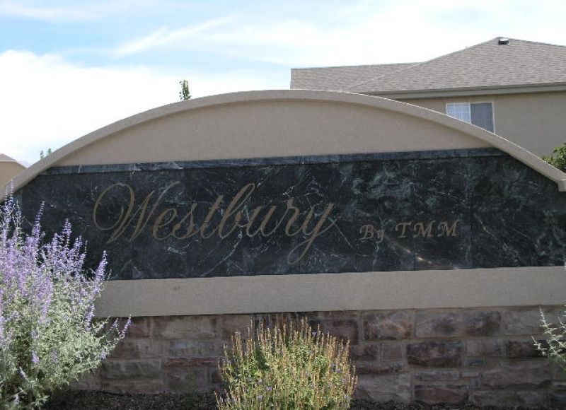 Sign for Westbury by TMM, a residential community with script lettering against a dark, textured background.