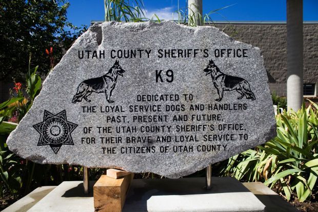 Memorial for K9 service dogs and handlers of Utah County Sheriff's Office, engraved on a large stone.