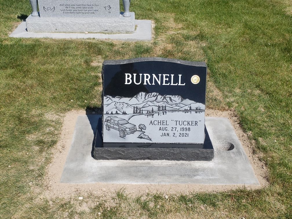 Black headstone in grass;